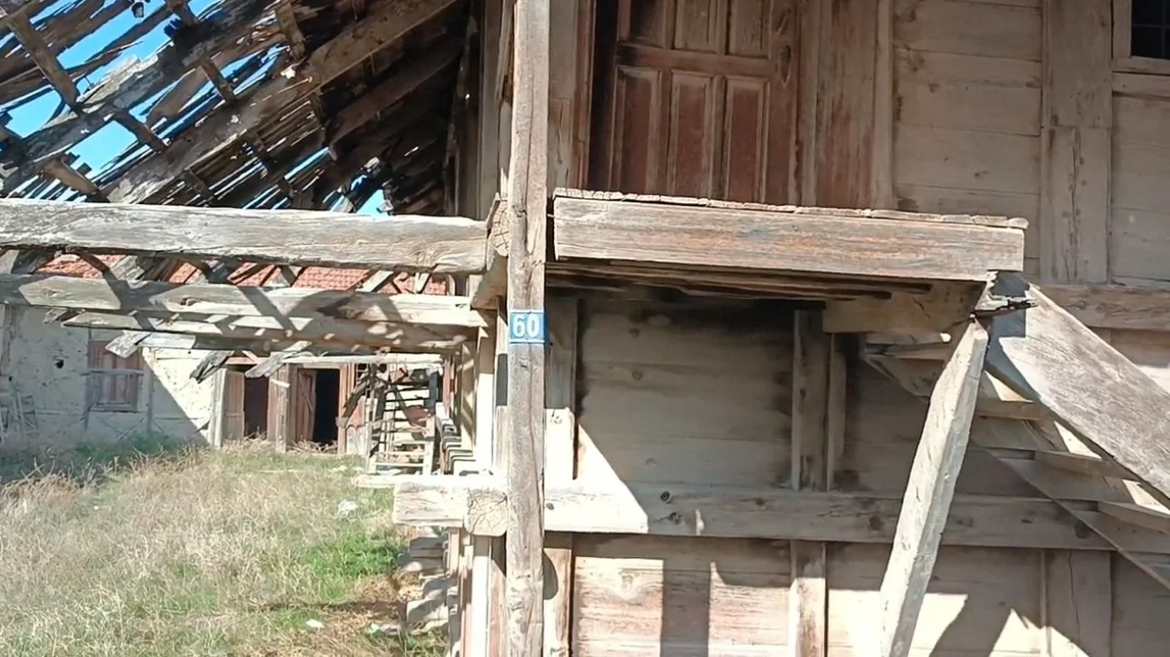 Ahşap yapıya ait, kısmen yıkılmış veya bakımsız bir eski bina, üst kısmında çatısı zarar görmüş ve açıkta kalan tahta destekler ile merdivenler var.