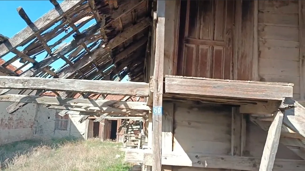 Ahşap yapıların çatısında hasar ve çatı kısımları açık, dış tarafta ahşap merdiven ve kapılar var, zeminde kuru otlar ve çimenler bulunuyor.