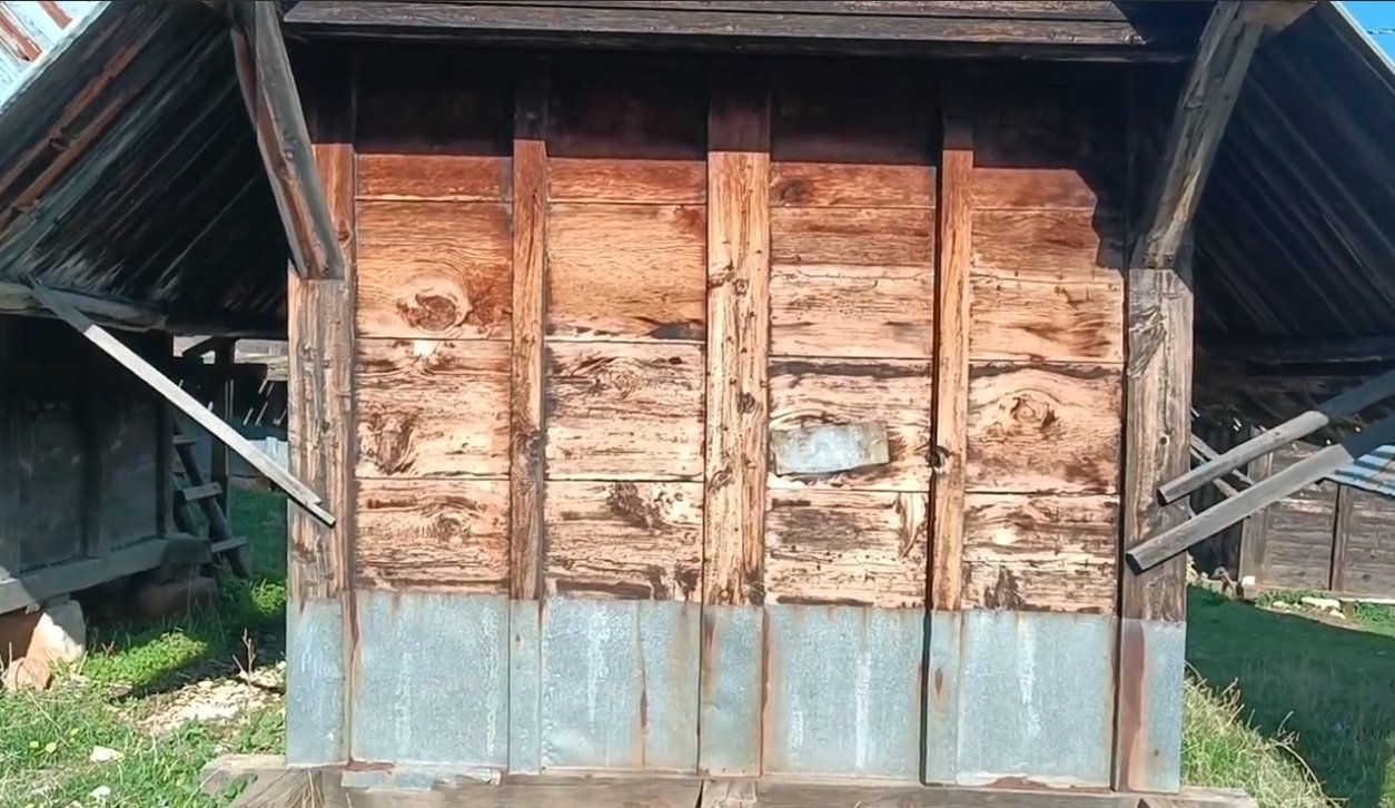 Ahşap ve metal malzemelerden yapılmış küçük bir kulübe, çevresinde yeşil alan var.