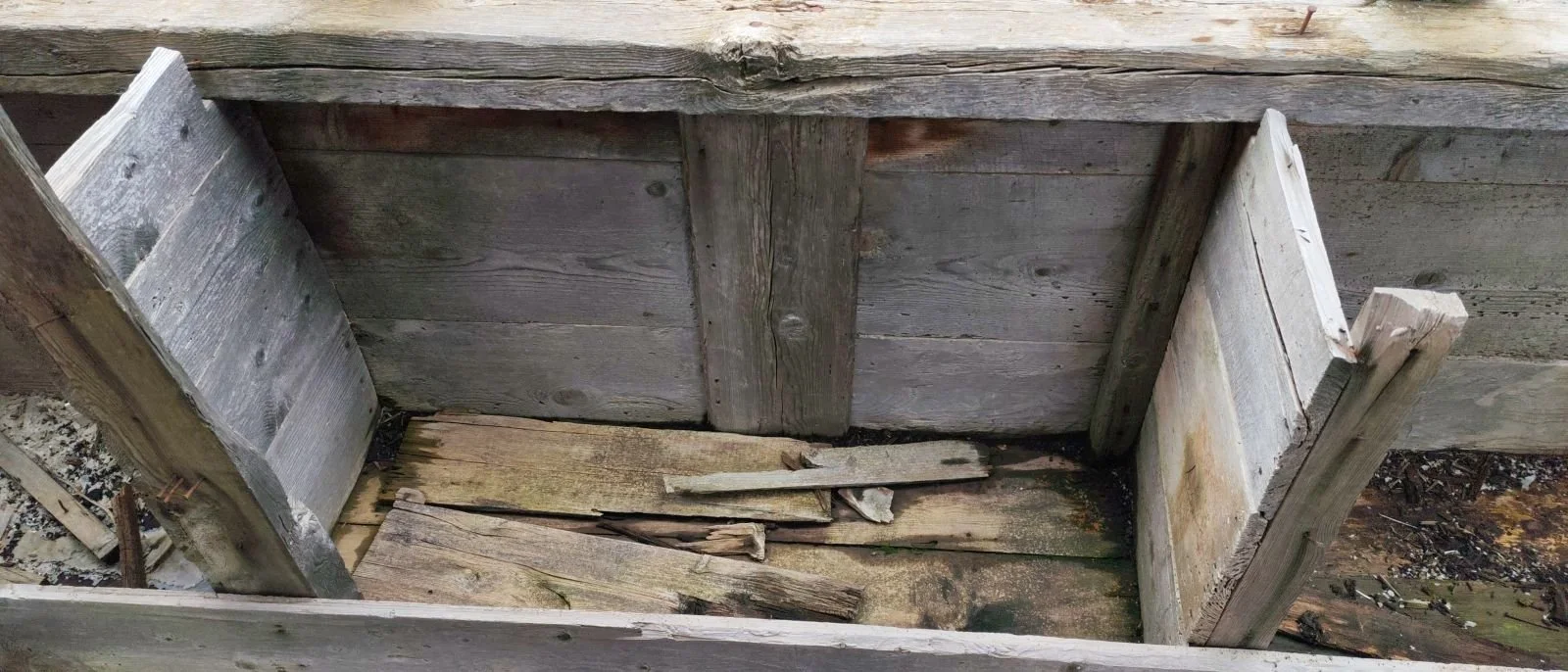 Ahşap bir kutu veya gömme alan, içi boş ve kötü durumdadır.