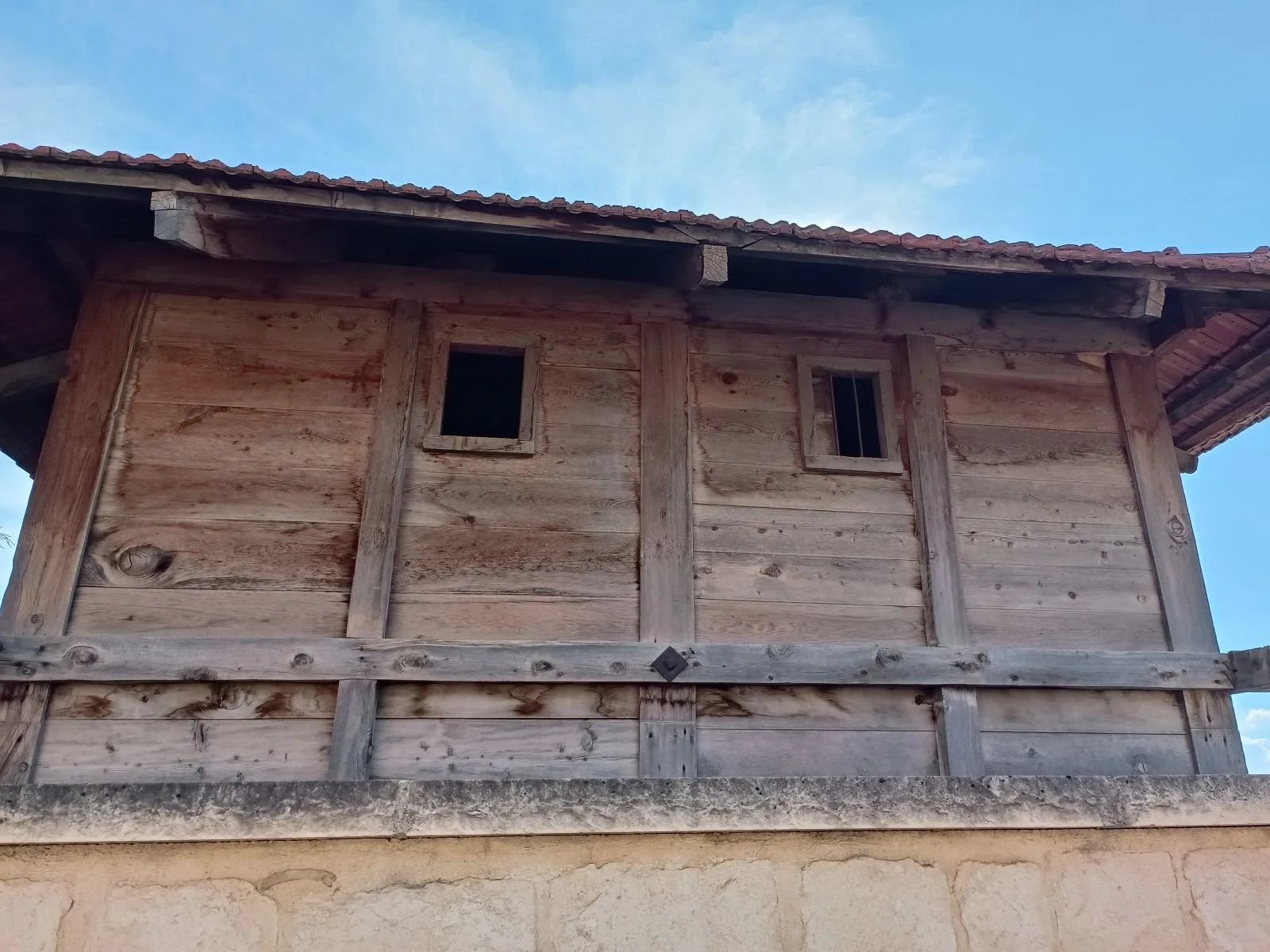 Ahşap inşa edilmiş ikinci katta küçük pencereler ve kırık çatılı bir bina.