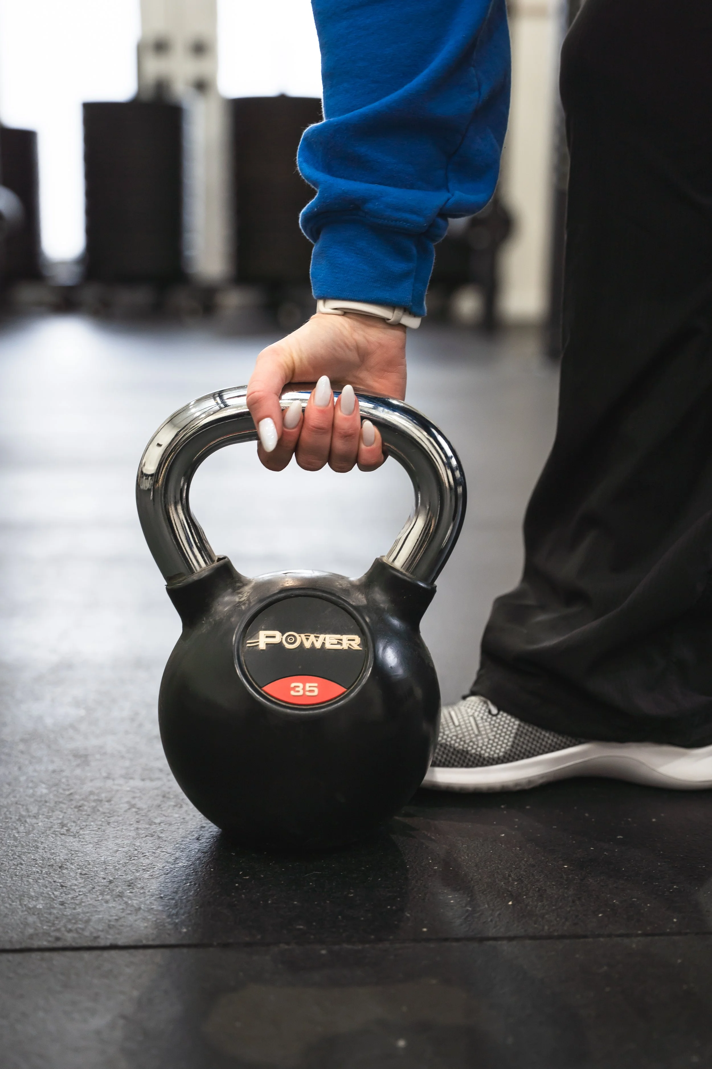 A Brantford women's strength training coach picks up a kettle bell.