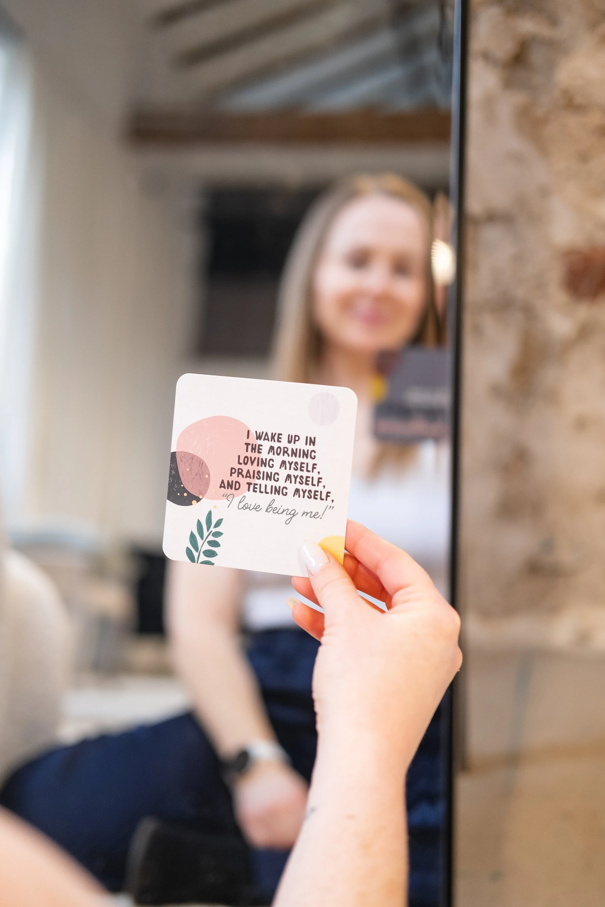 Female group fitness trainer near Hamilton Ontario looking into a mirror holding an affirmation card in Brantford.