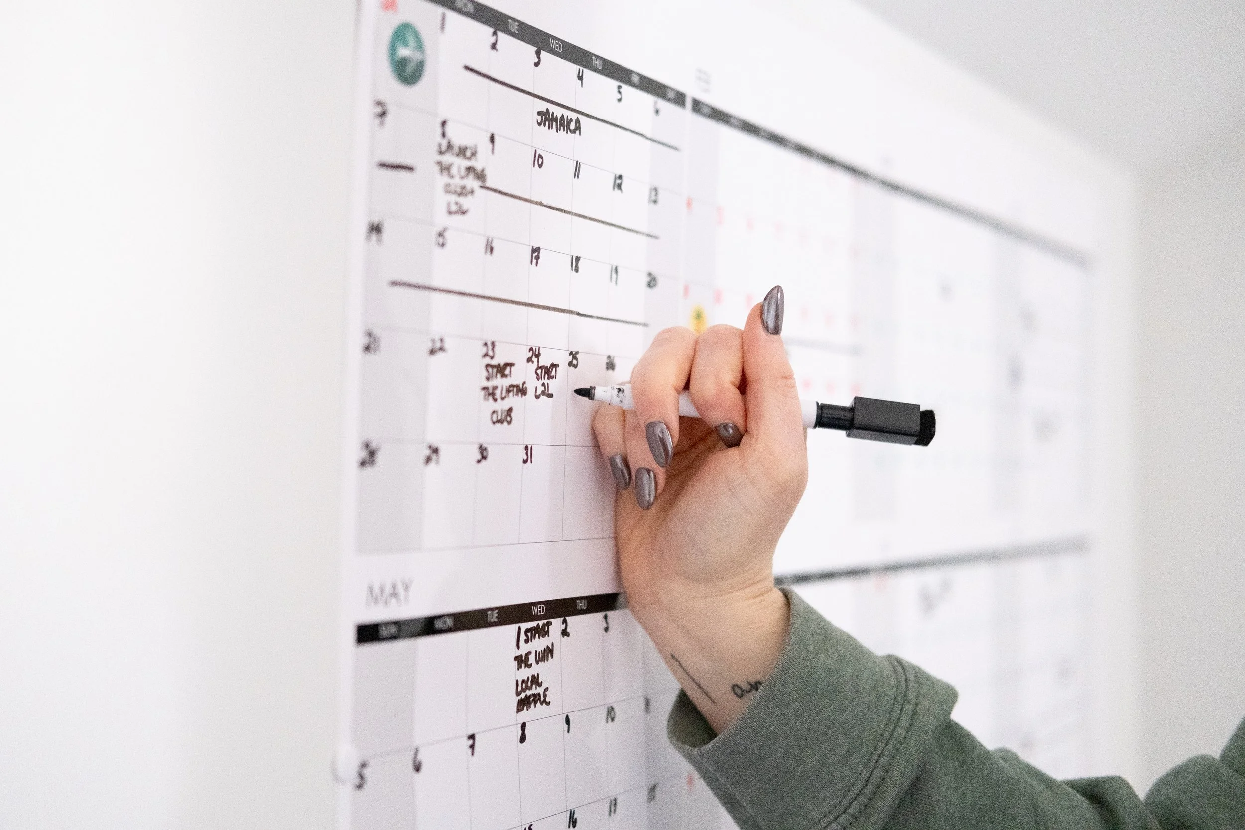 Hamilton women’s fitness coach’s hand writing on a calendar for her group fitness programs