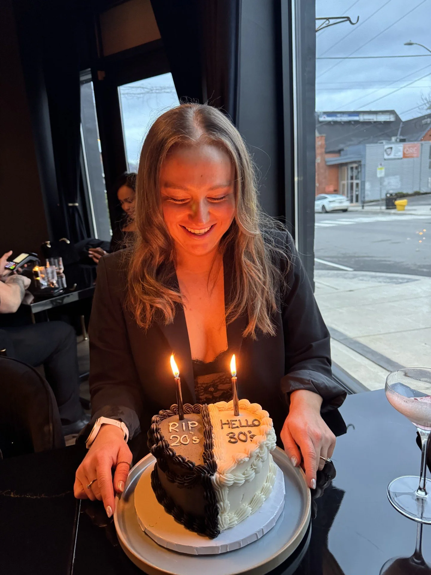 A women's fitness Coach smiling at her 30th birthday cake in Brantford Ontario