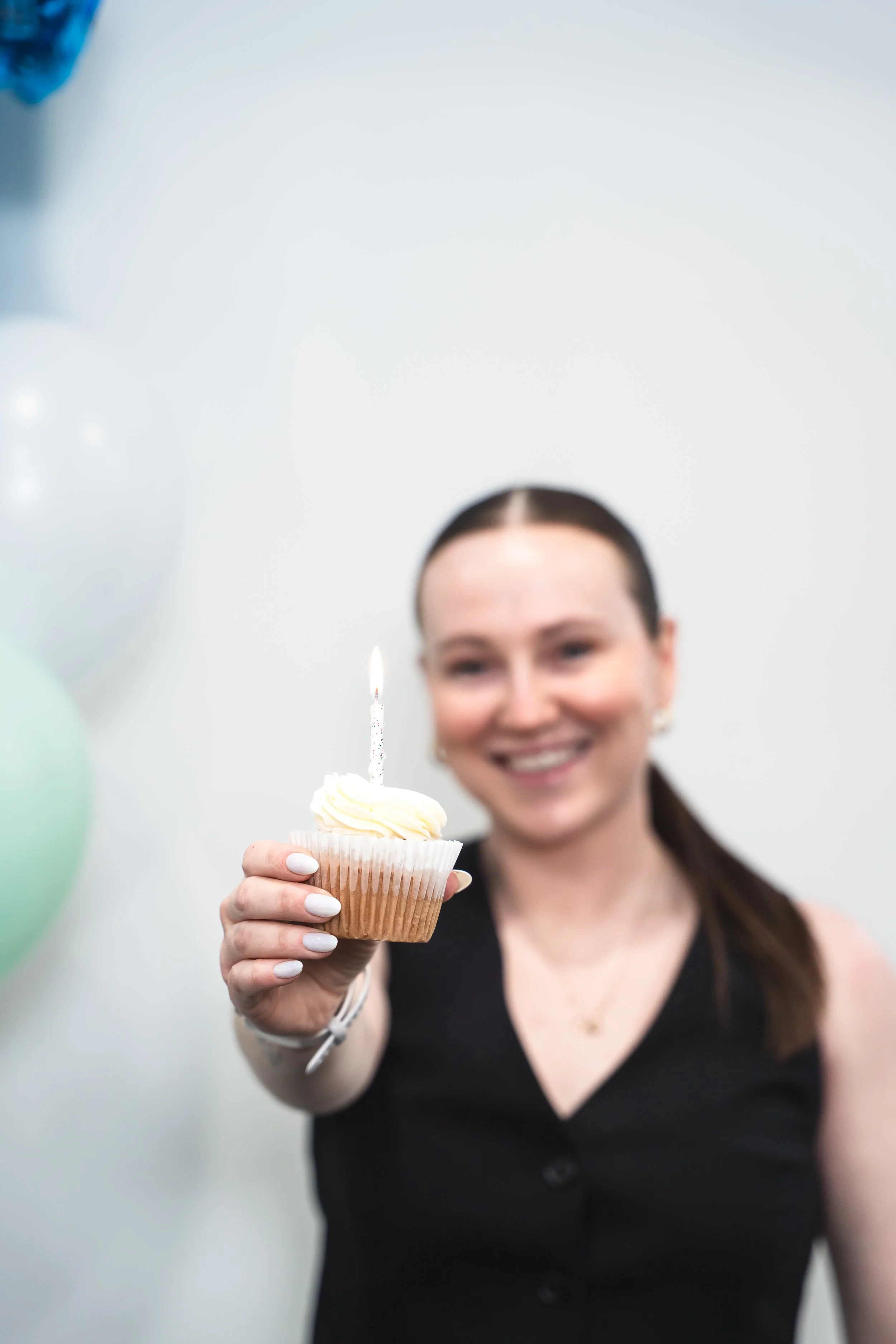 A women's fitness coach in Brantford Ontario holding a celebratory cupcake with a candle