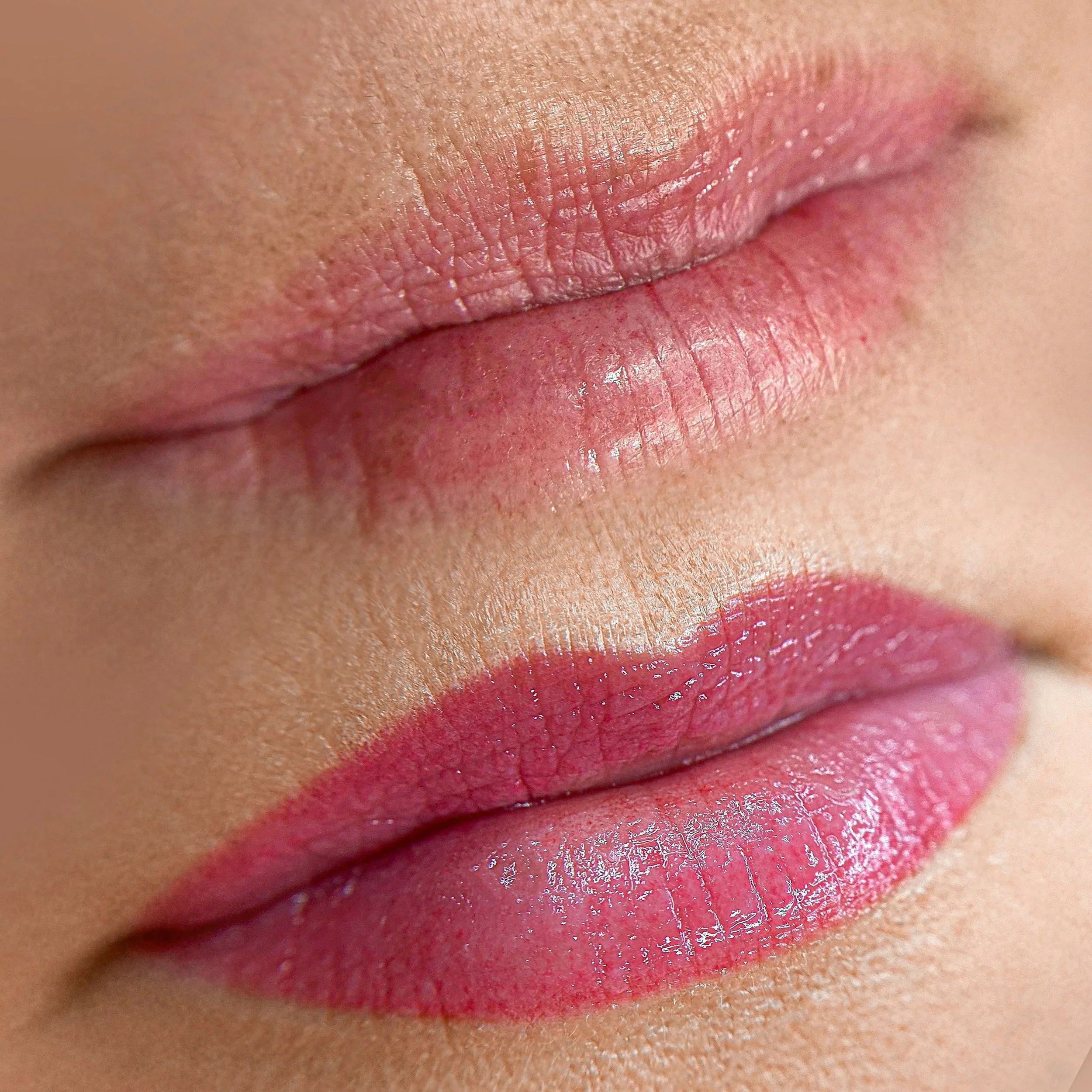 Close-up of a person's lips with pink lipstick, showing detailed skin texture.