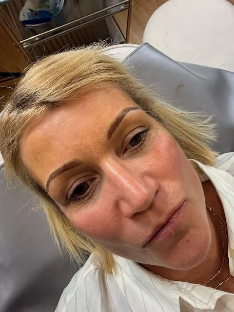 Close-up of a woman with blonde hair and light skin lying on a medical chair, with a neutral expression.