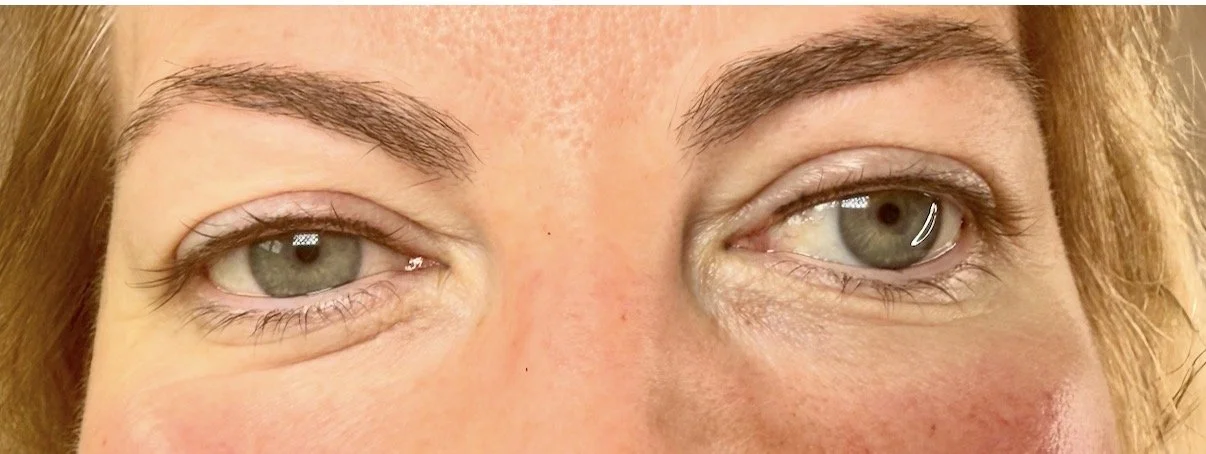 Close-up of a person's face with light skin, light blue eyes, and brown eyebrows, showing the eyes and part of the nose.