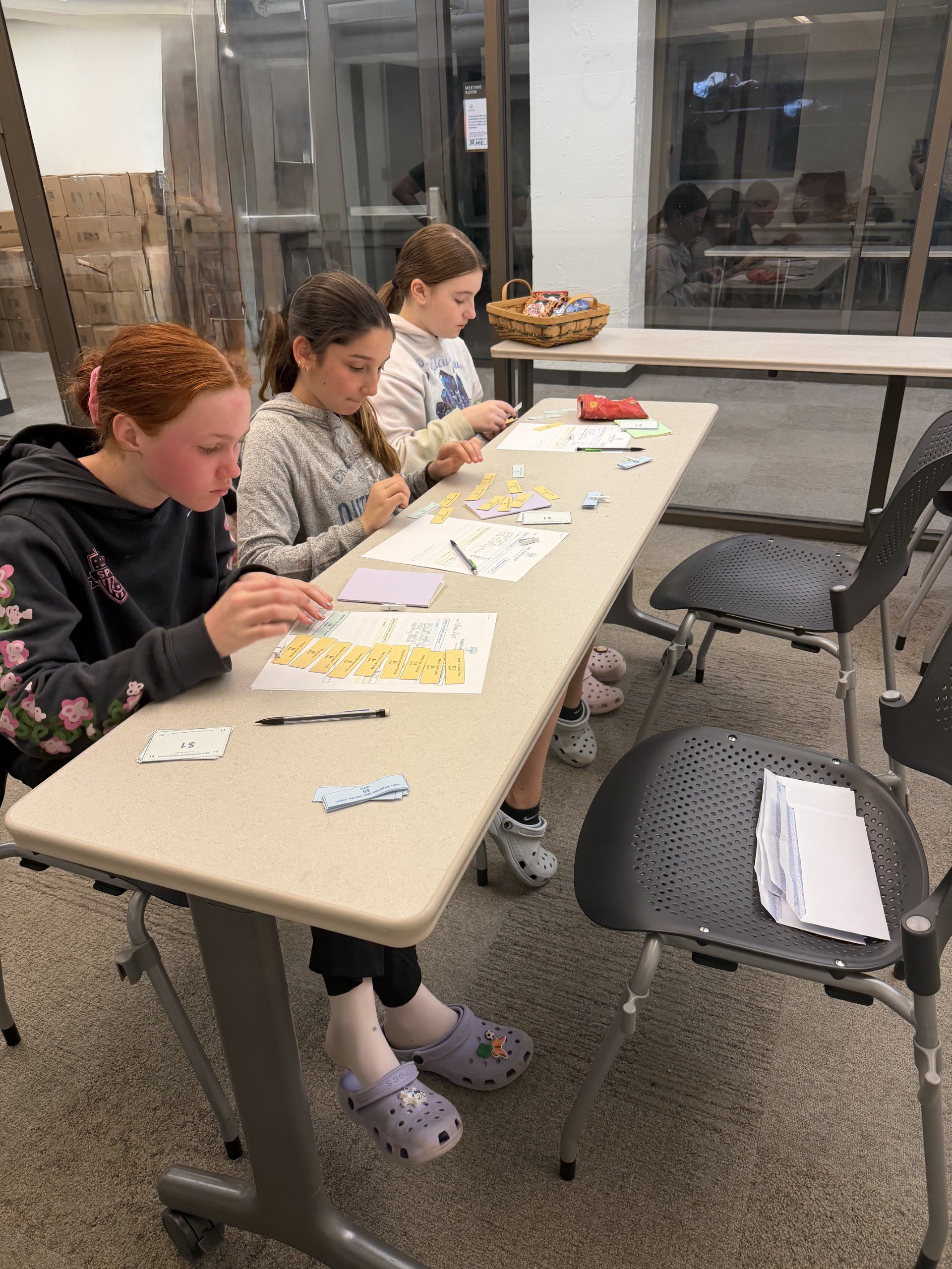 6th graders completing a budgeting game sitting at a table.