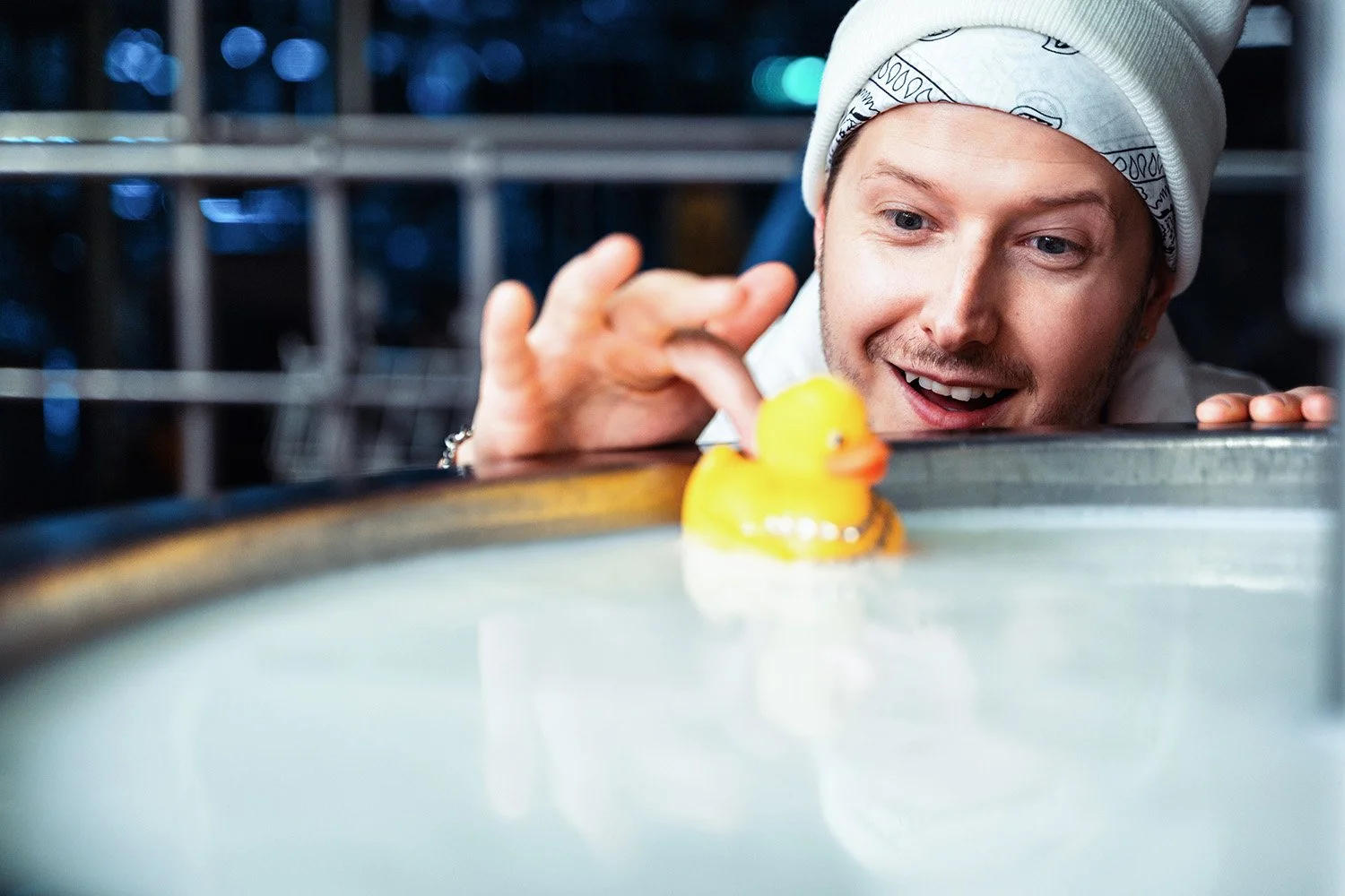 Mies katsoo leikkivaa keltaista ankkaa kylpyammeessa.