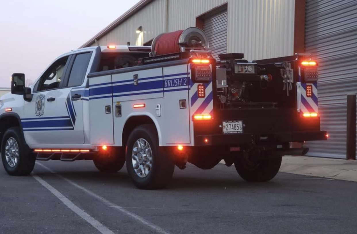 Fire truck labeled BRUSH 2 parked outside a building with closed metal doors at dusk.