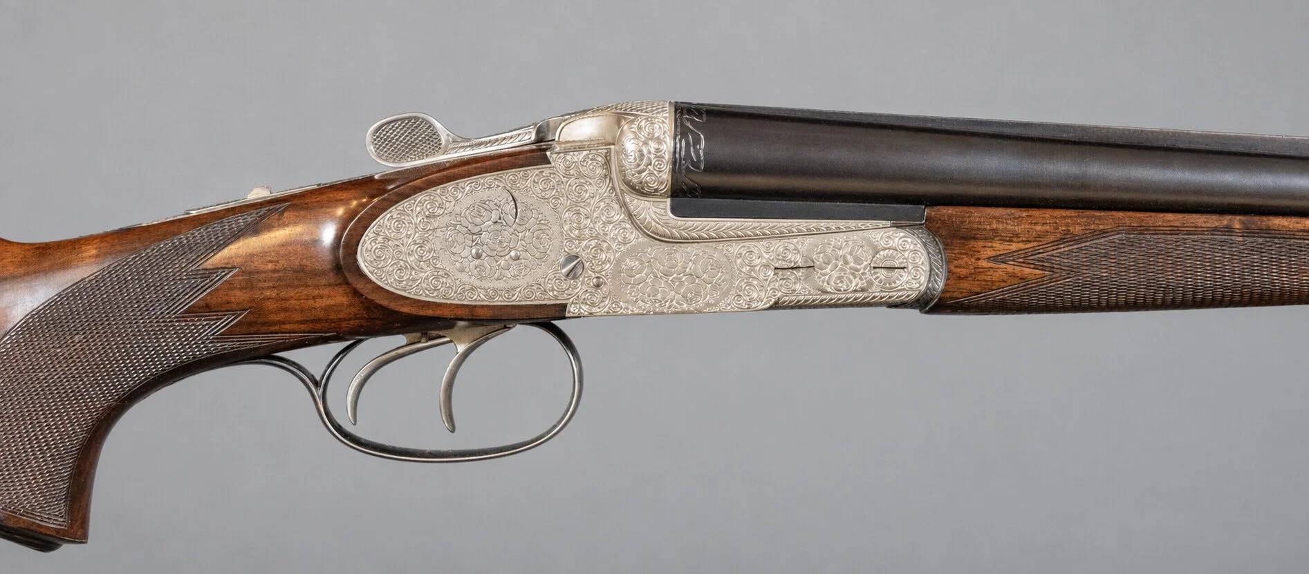 Editorial study of a sporting-arm action and engraving against a light neutral background