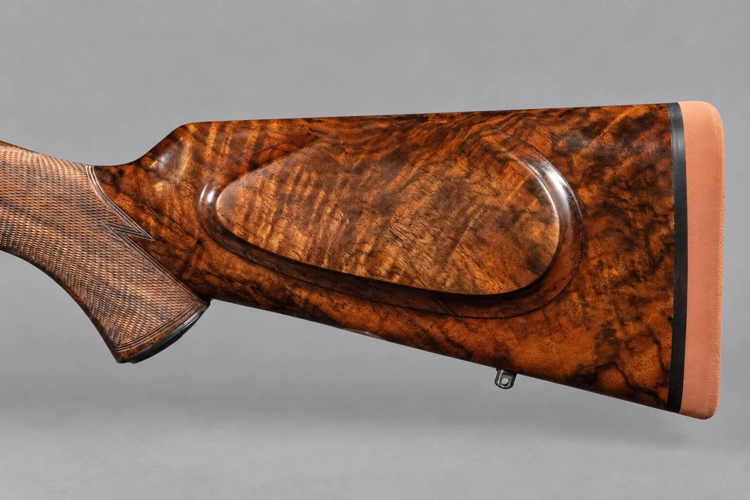 Editorial study of a walnut stock and cheekpiece against a light neutral background