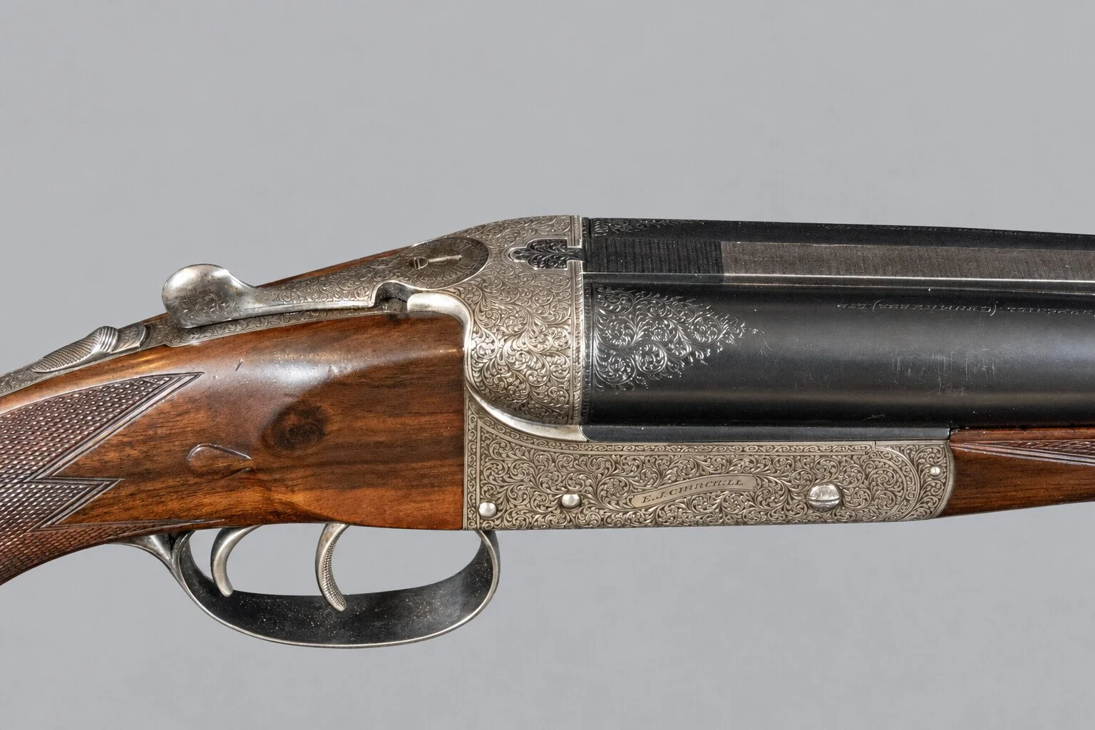 Editorial study of sporting-arm engraving and action against a light neutral background
