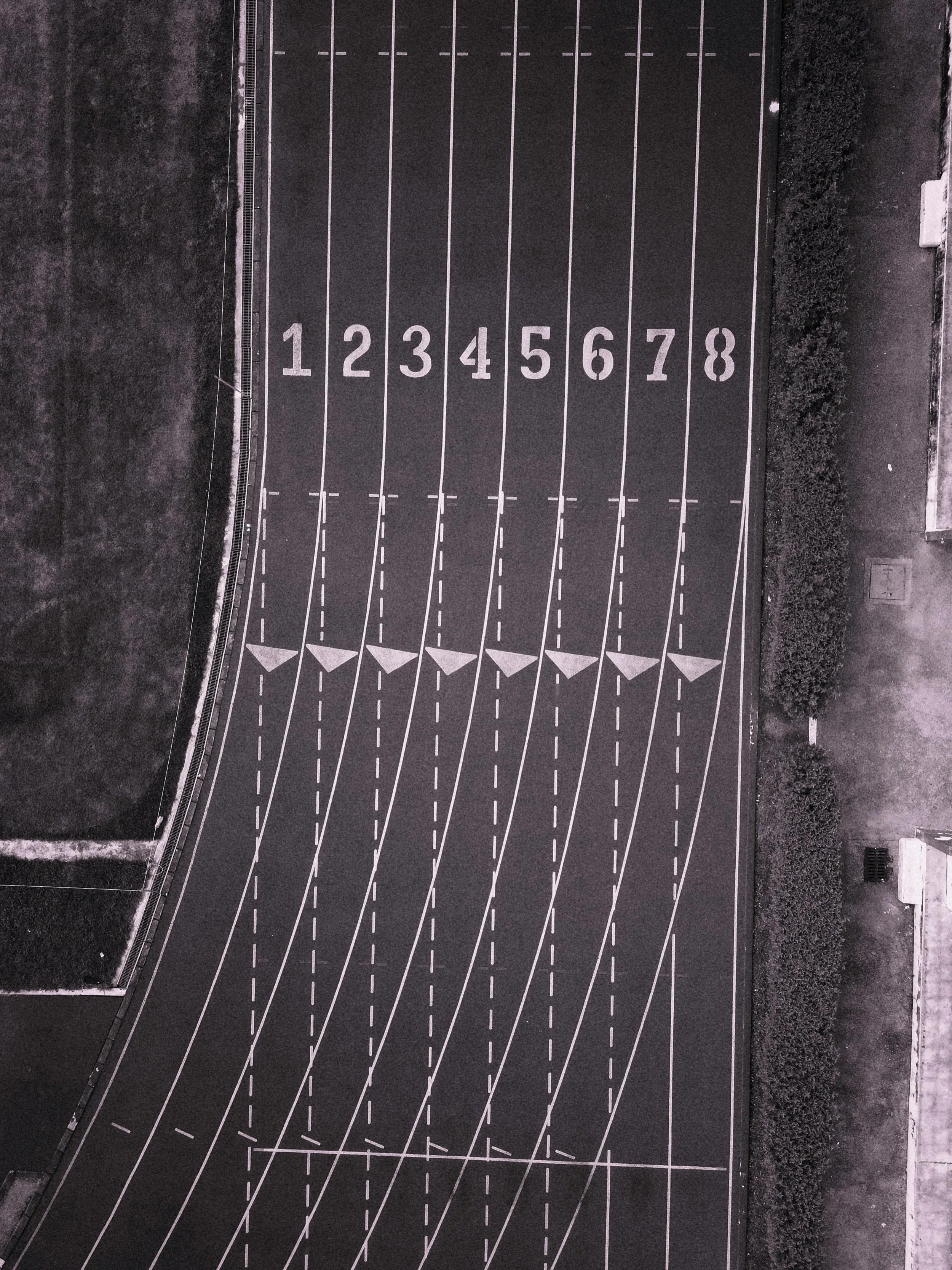 An aerial view of an empty outdoor running track with lanes numbered 1 to 8.