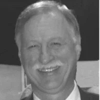 A smiling man with light-colored hair and a suit