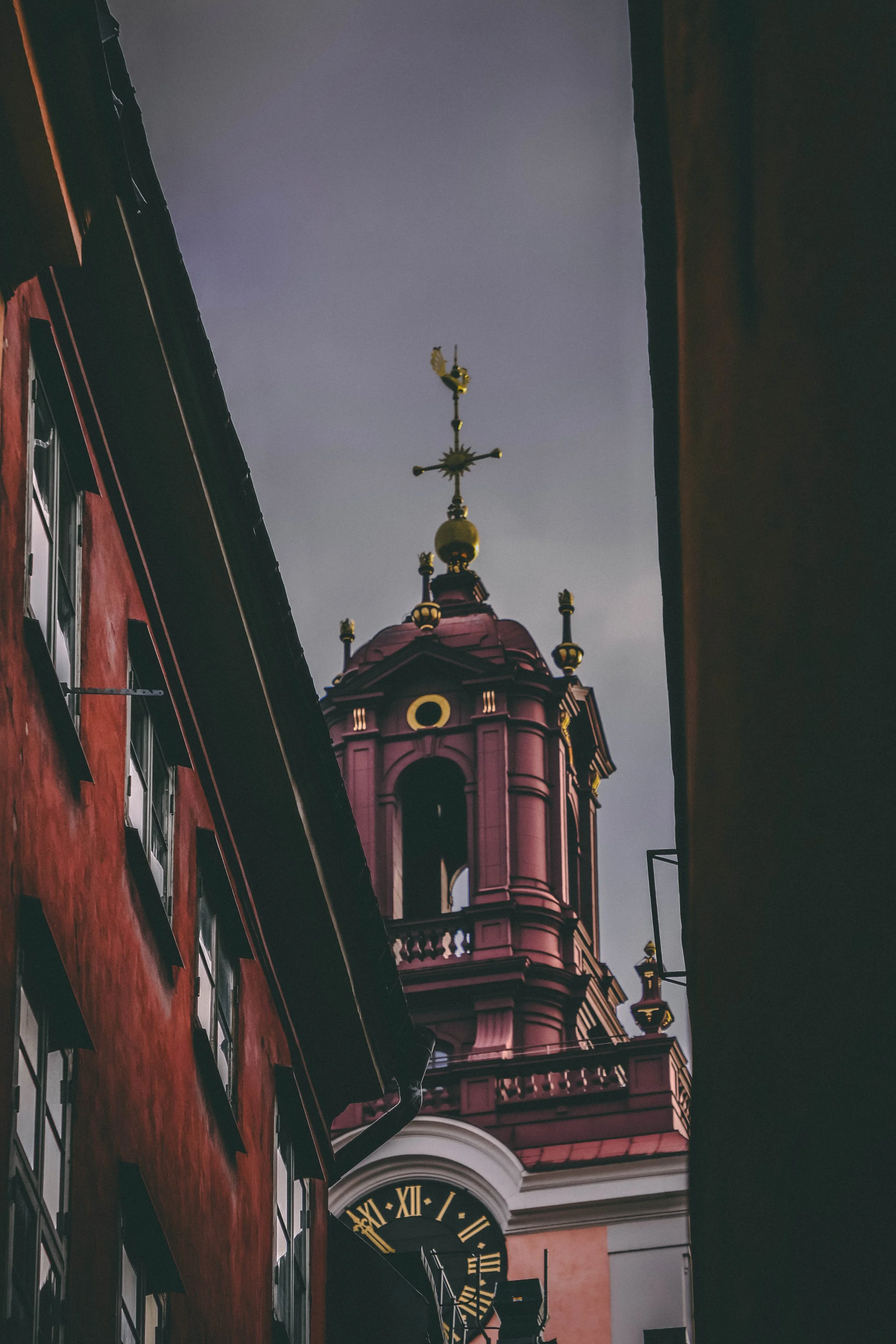 "The Clocktower’s Last Chime"
In the heart of the old city, where the rooftops leaned like tired shoulders and the alleyways whispered secrets with every gust of wind, stood a crimson-and-gold clocktower. It had watched over Stockholm for centuries