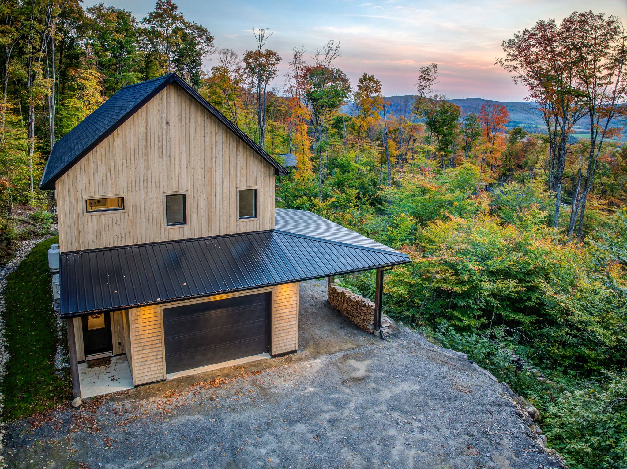 Maison de style scandinave au sommet d’une montagne à Mont Tremblant, avec vue sur le feuillage d’automne.