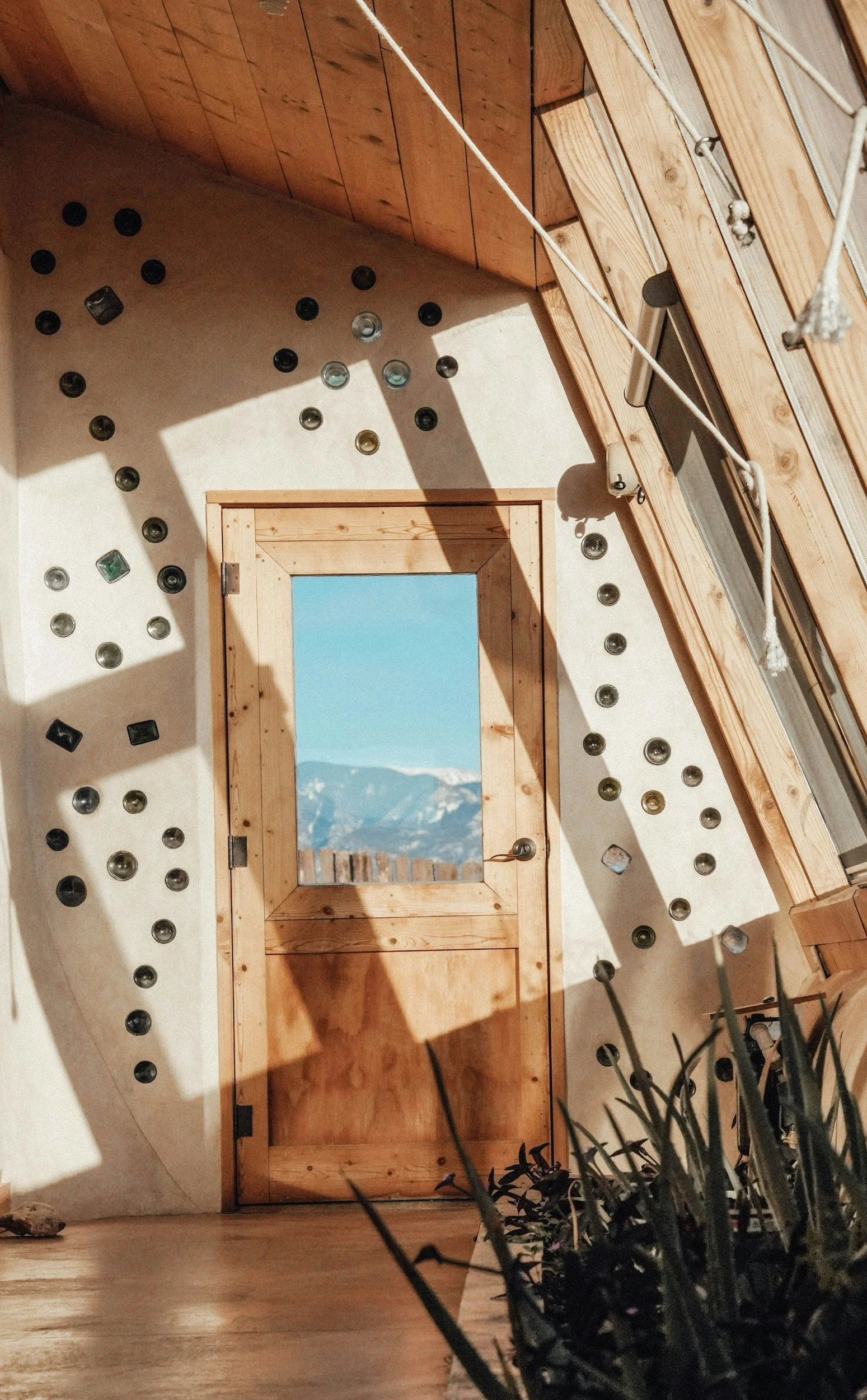 Earth ship bottle wall surrounding wooden door in the greenhouse