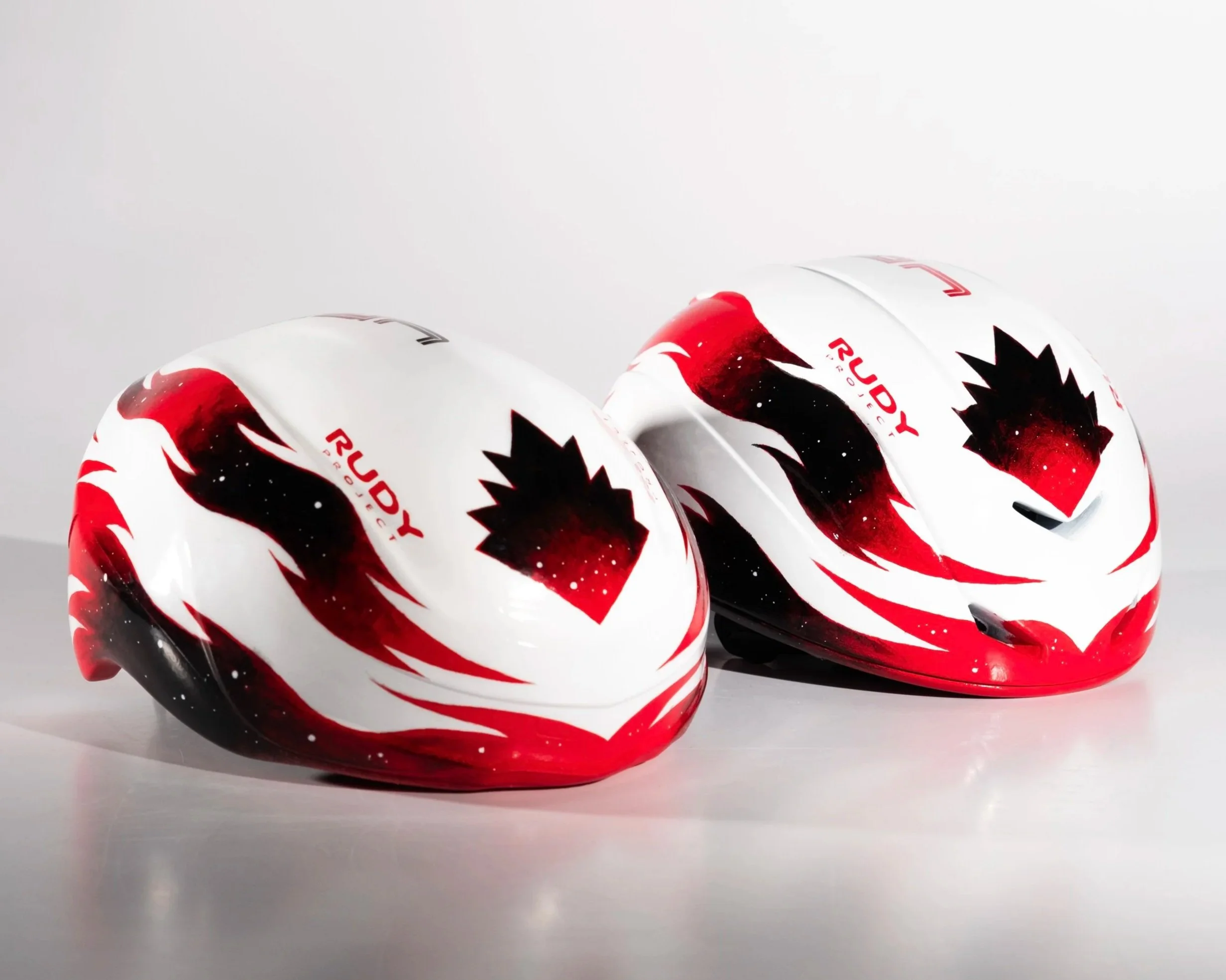 Casque de vélo blanc avec un design rouge, noir et noir, portant le logo