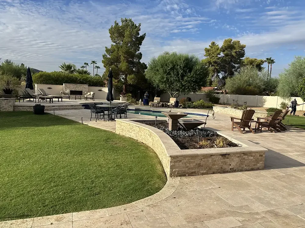 Backyard with a swimming pool, patio furniture, and trees under a partly cloudy sky.