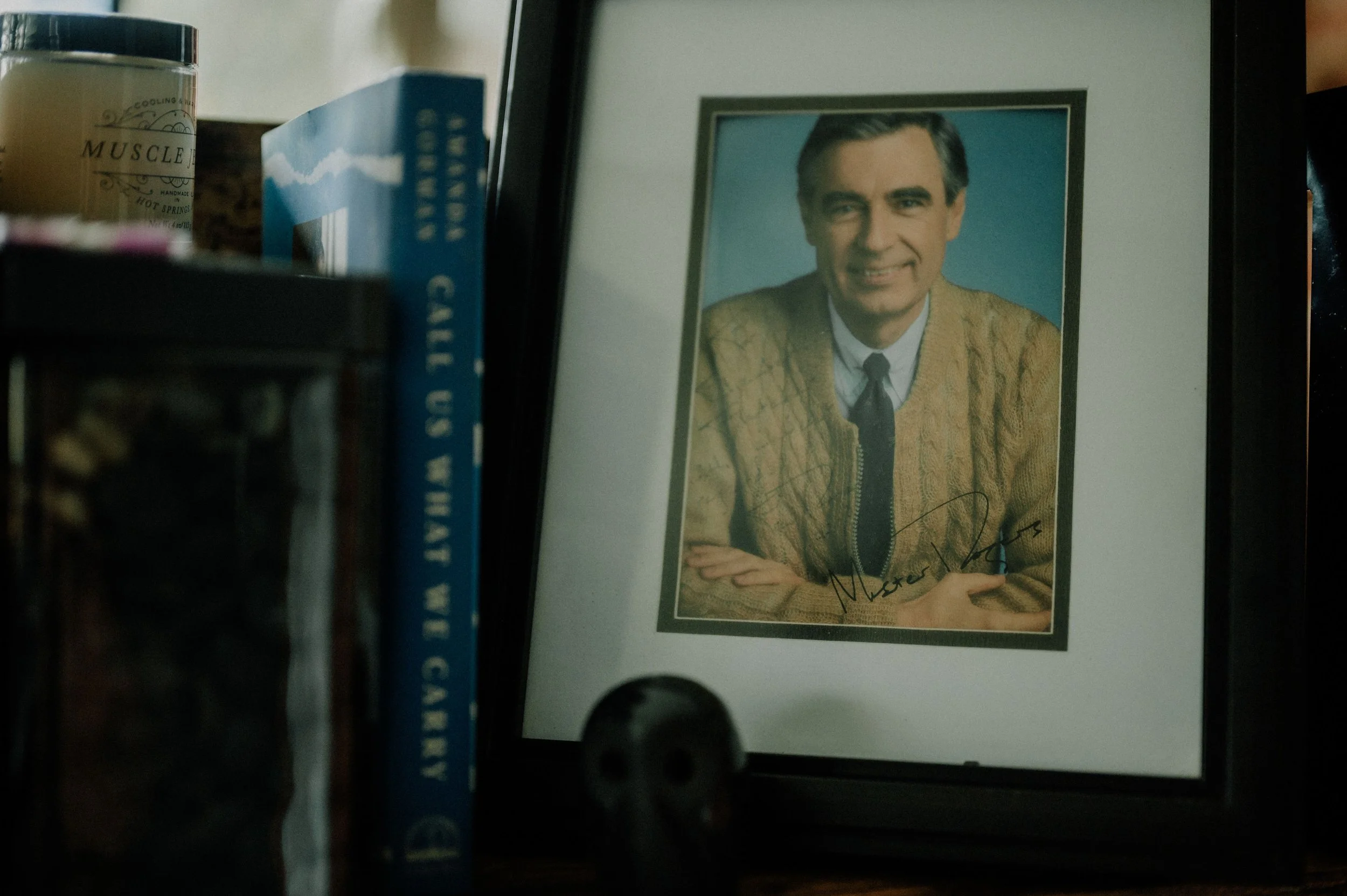A close-up view of an autographed photo of Mr. Rogers on display on a bookshelf.