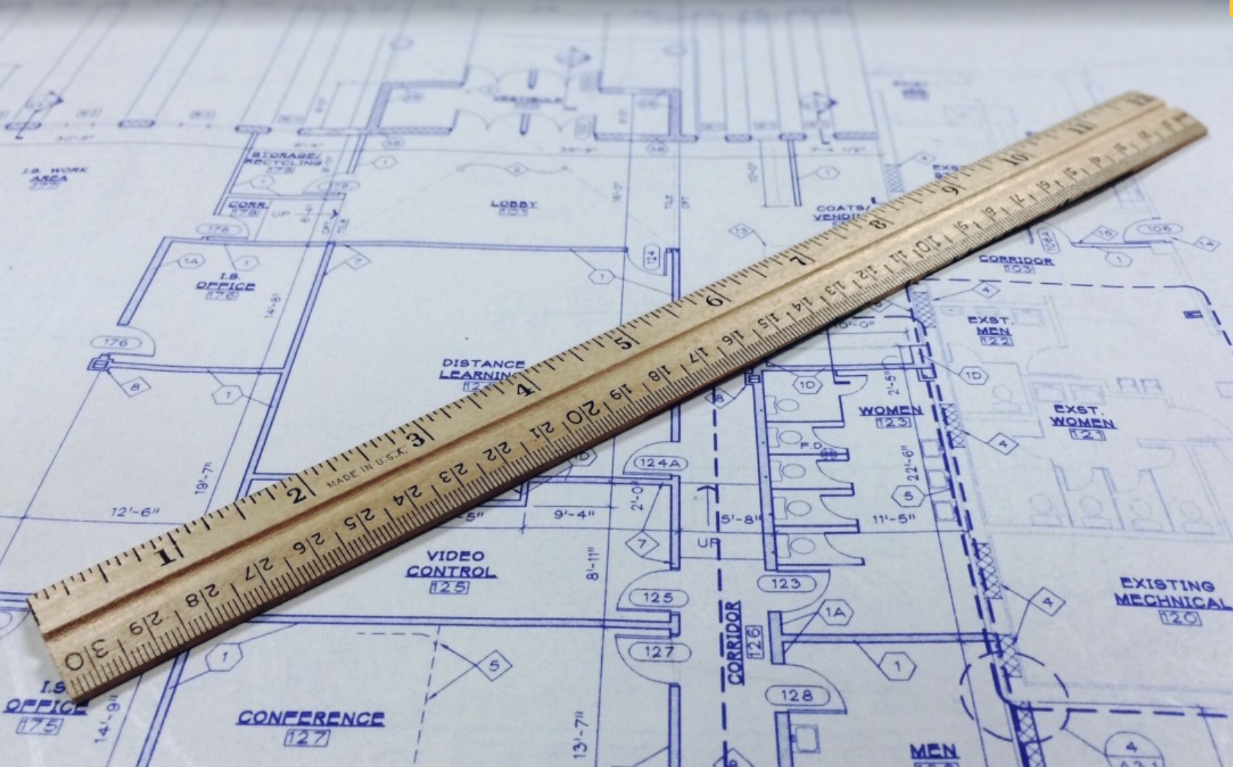 Blueprint of a building layout with a wooden ruler placed diagonally across it.