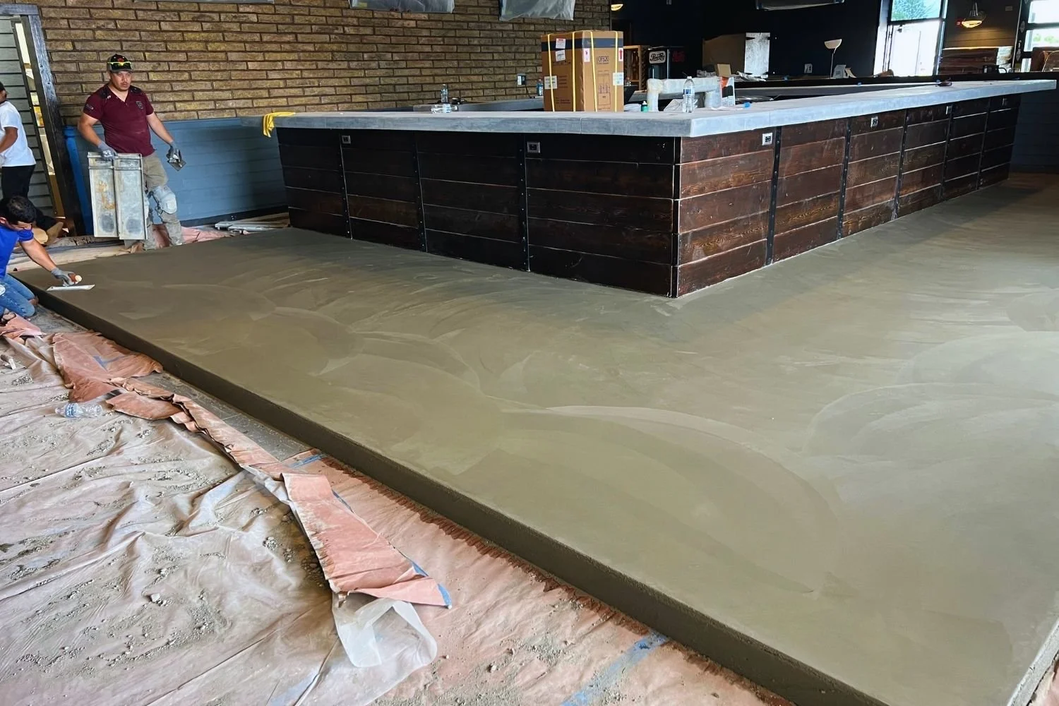 Workers installing polished concrete flooring in commercial space by JECAM