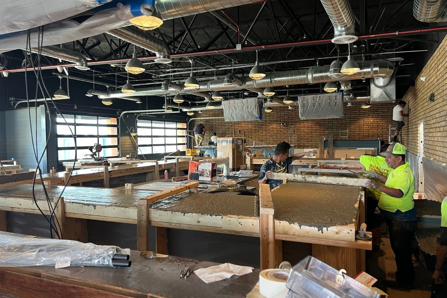 Construction workers pouring and leveling concrete countertops in a commercial building by JECAM
