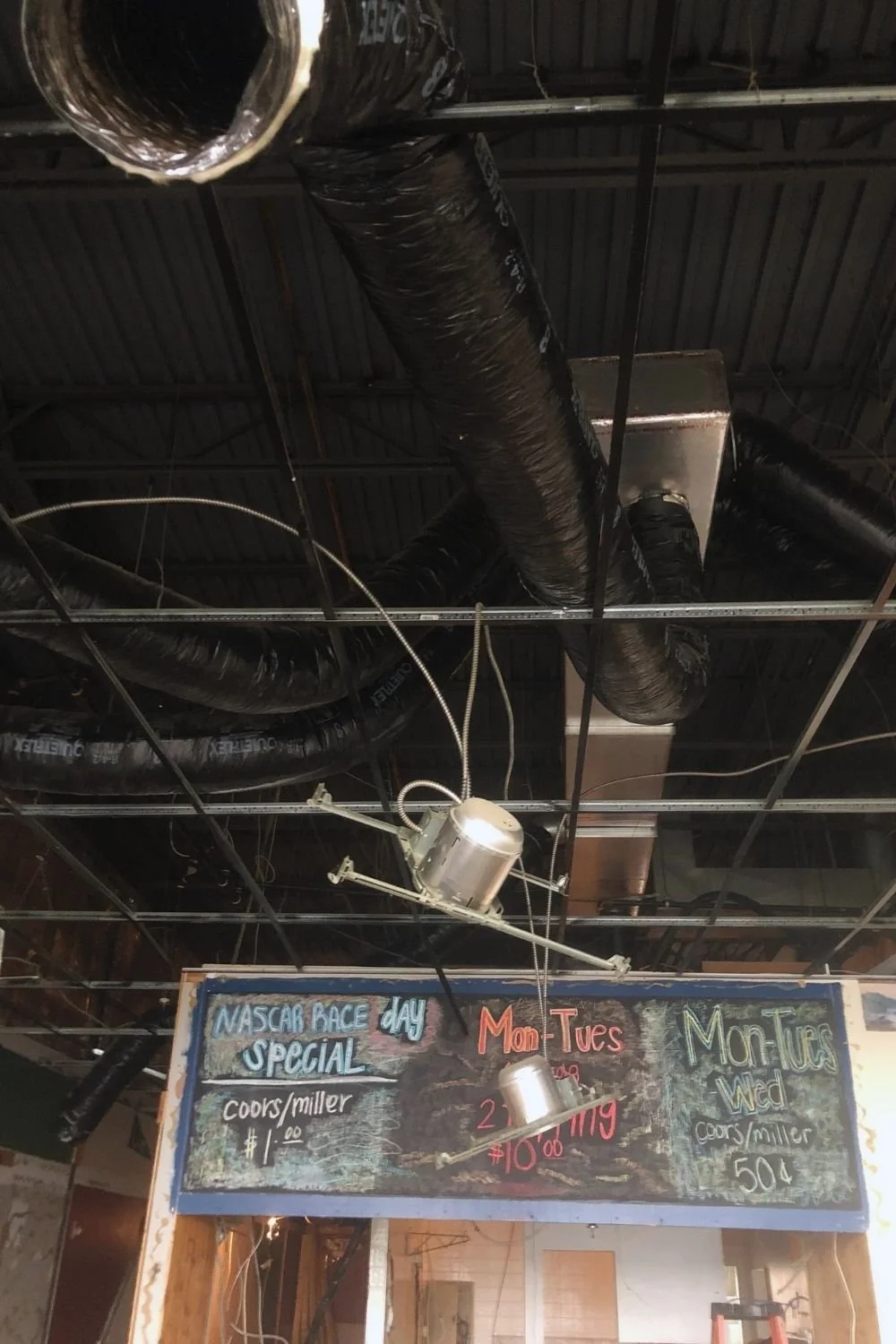Ceiling renovation with exposed ductwork and electrical wiring in commercial bar area by JECAM