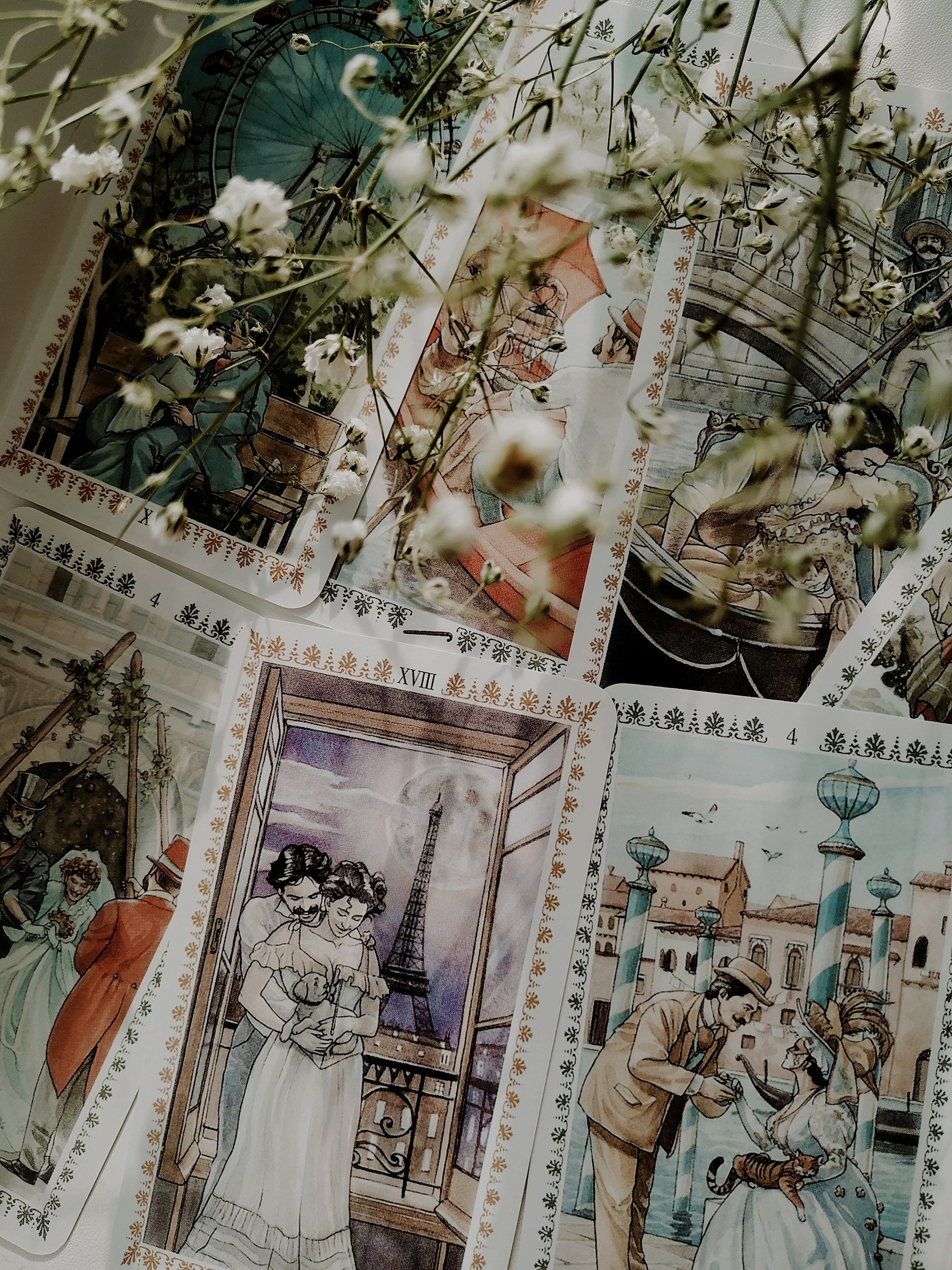 A collection of vintage travel-themed postcards and illustrations, featuring scenes of people in Paris, France, including the Eiffel Tower, and a young couple on a balcony, with white flowers and branches partially obscuring the view.