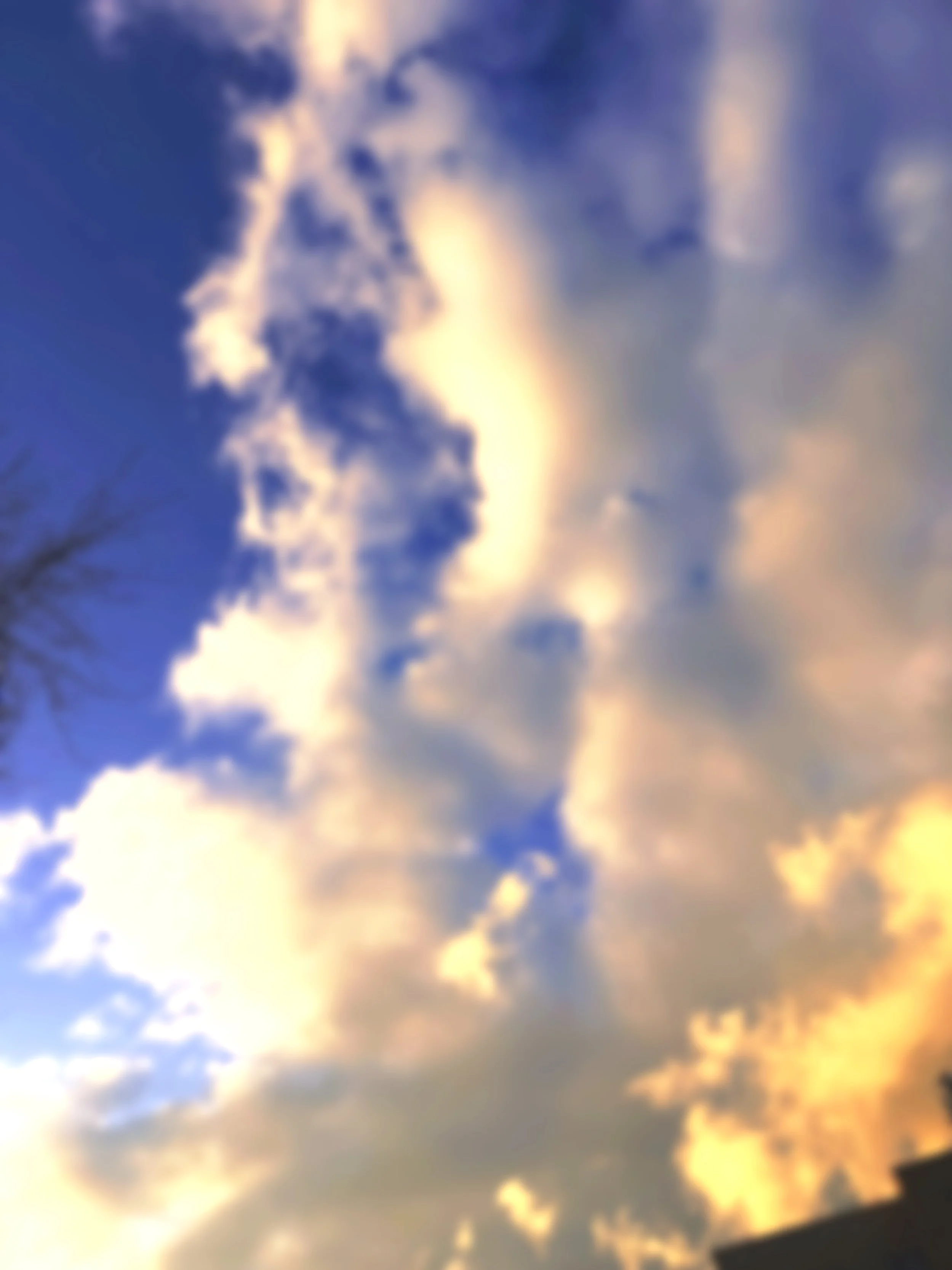 A partly cloudy sky during sunset with a mix of clouds and sunlight, creating a golden glow.