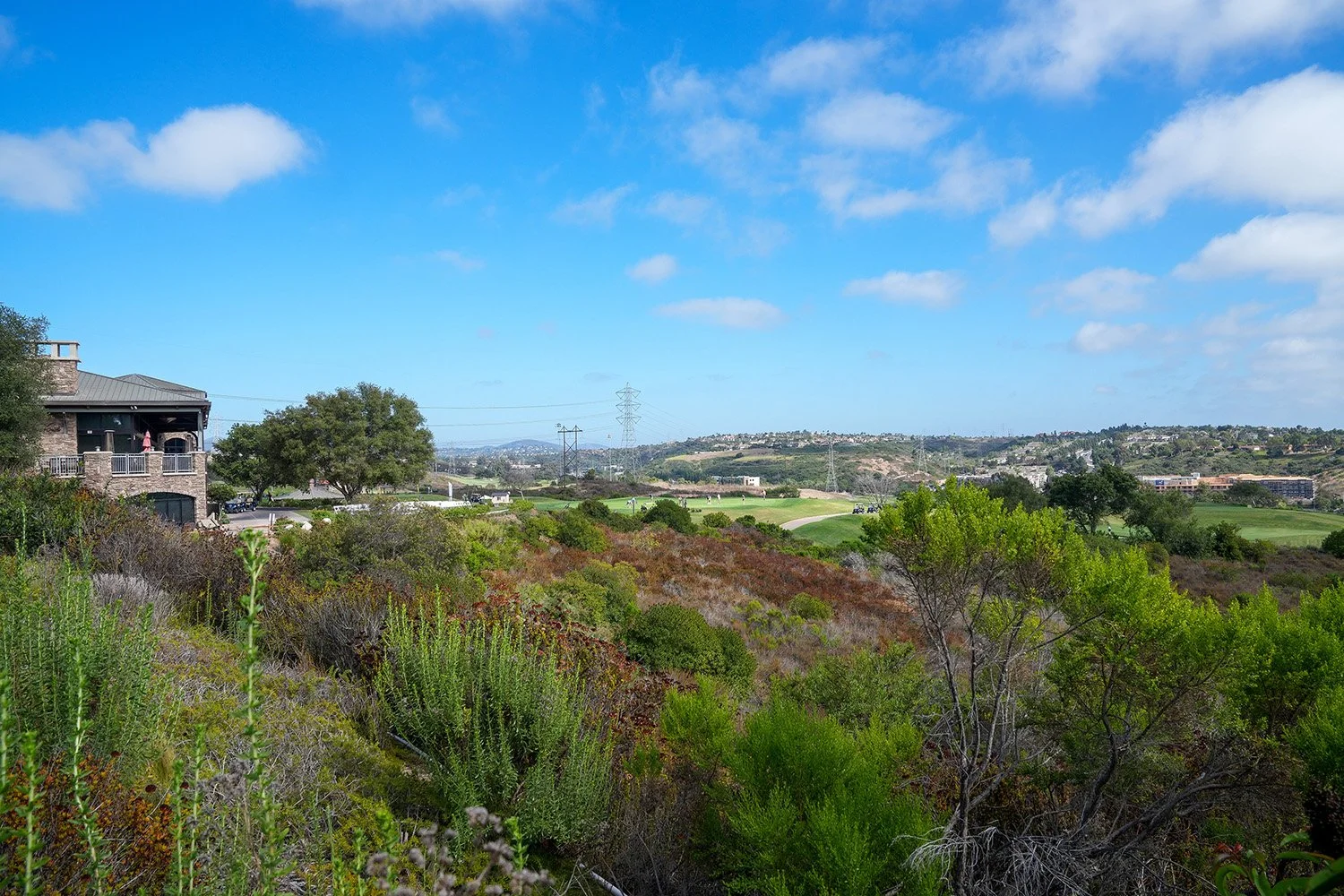 An elevated, daytime panoramic view of the hilly landscape surrounding The Crossings at Carlsbad golf course in Southern California.