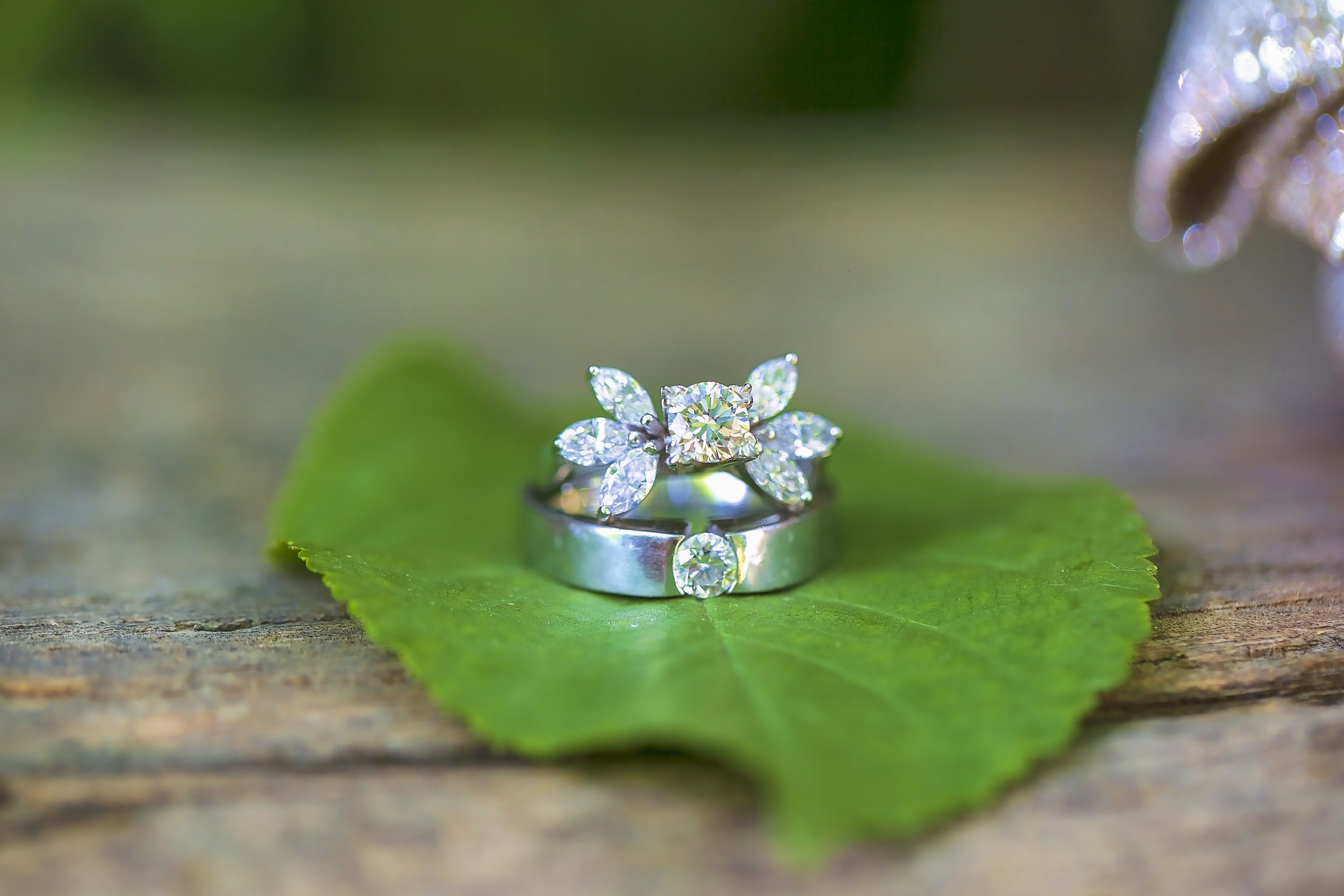 Unique diamond engagement ring with marquise and cushion cut stones photographed outdoors on a leaf.