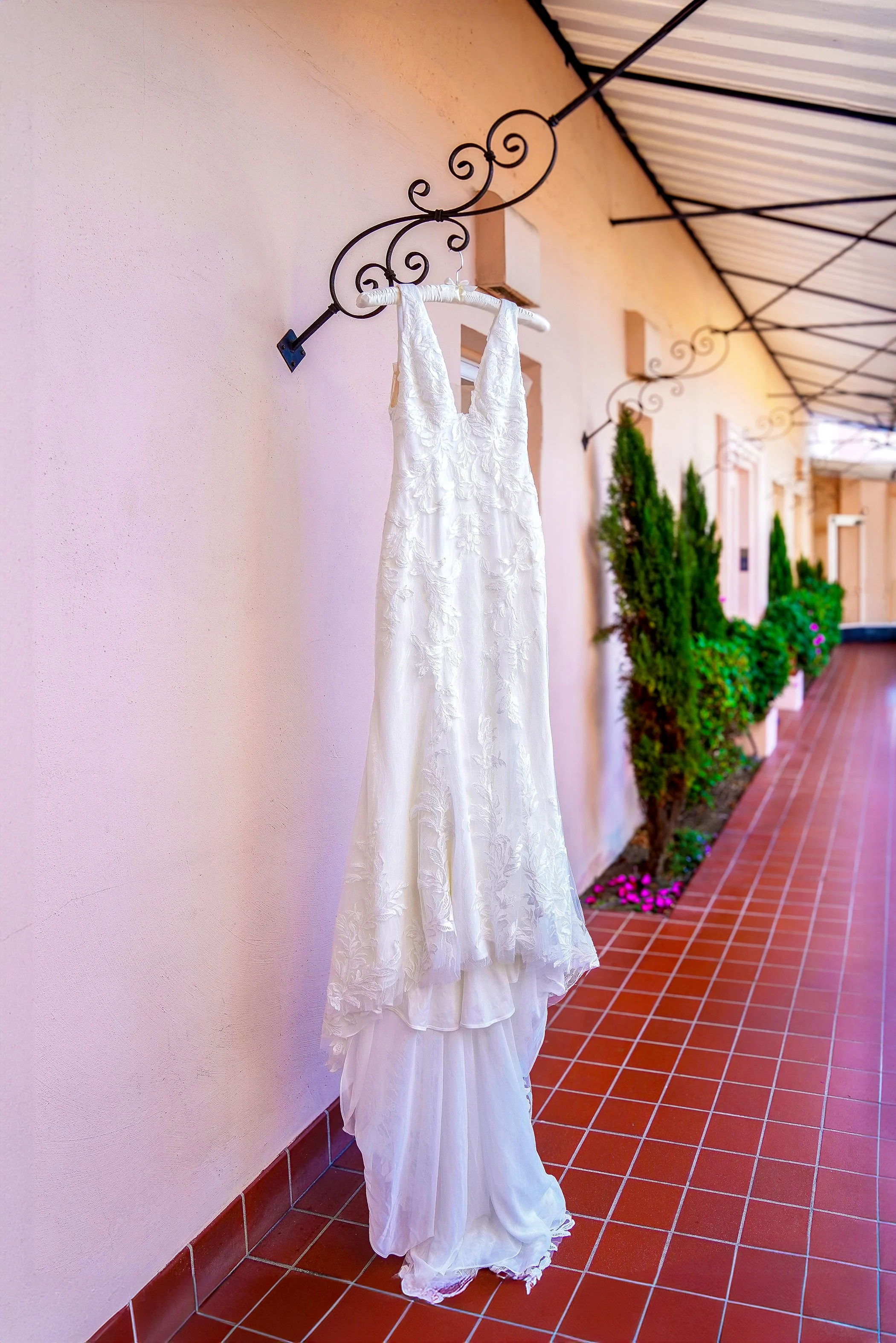 Elegant lace wedding gown on display at La Valencia Hotel in La Jolla, featuring a classic V-neck silhouette and intricate floral embroidery.