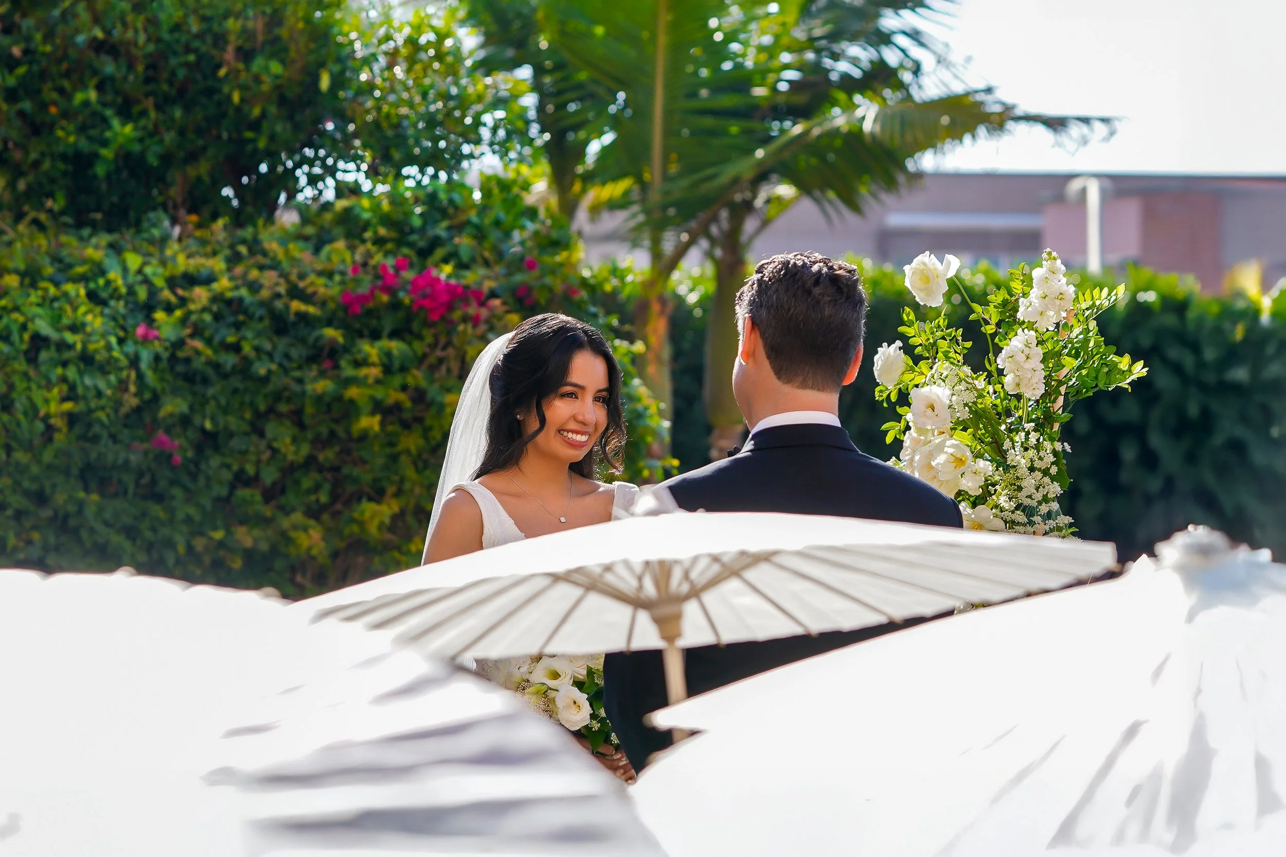Outdoor garden wedding ceremony in San Diego featuring a bride in a white gown and groom in a black tuxedo.