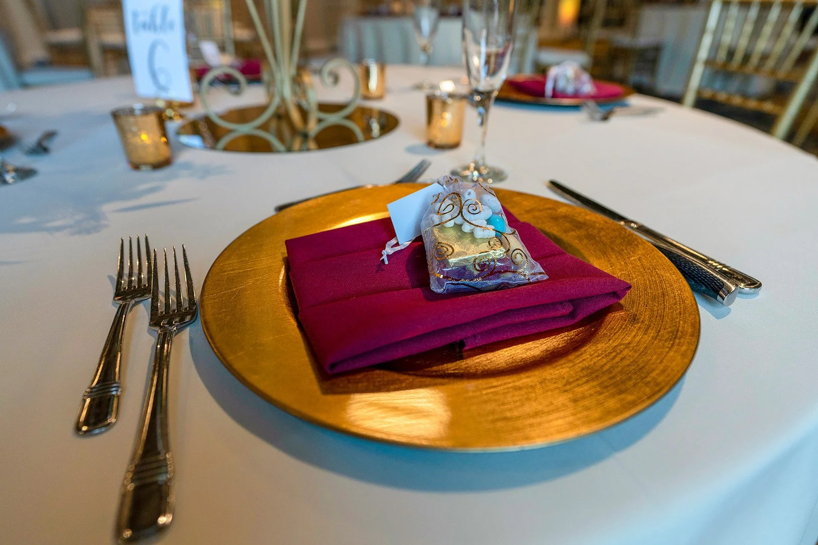 The foreground centers on a single place setting at a round table draped in a white tablecloth.