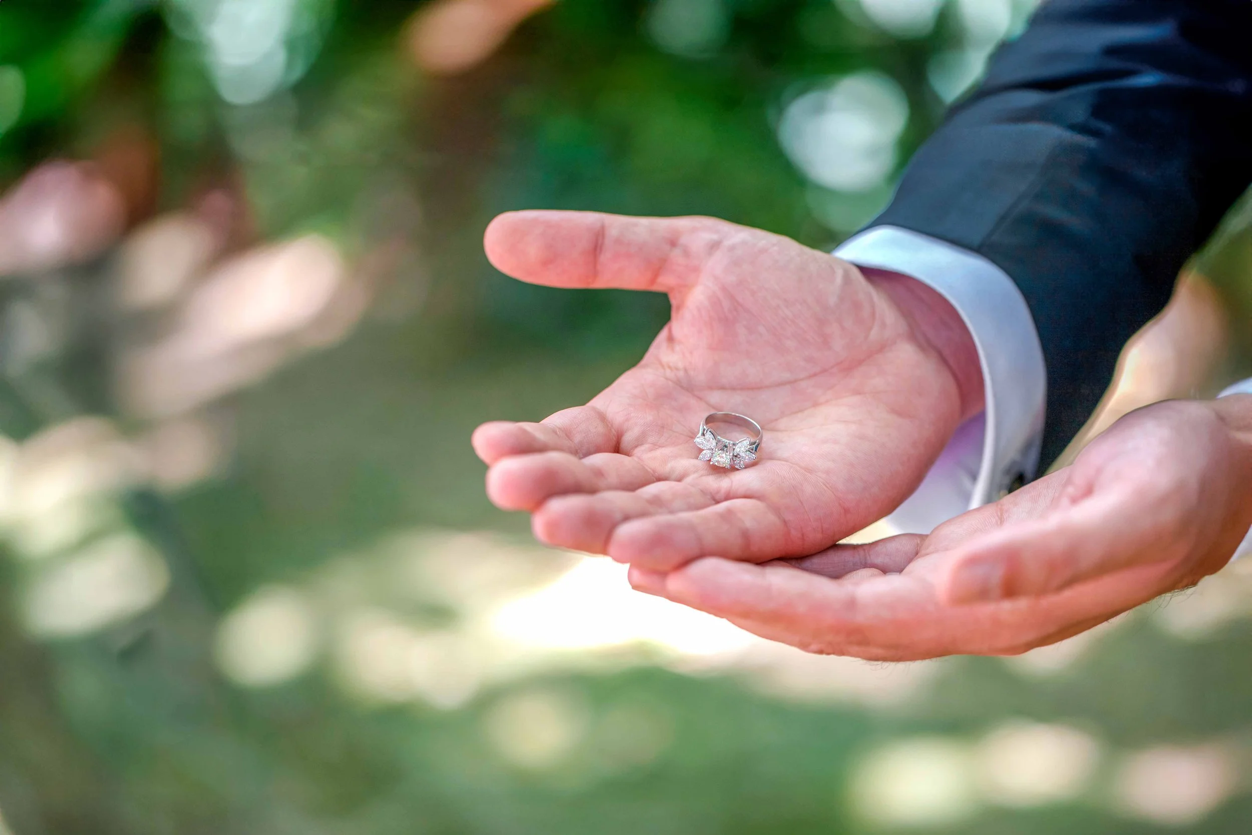 A wedding ring in the hands of the groom.