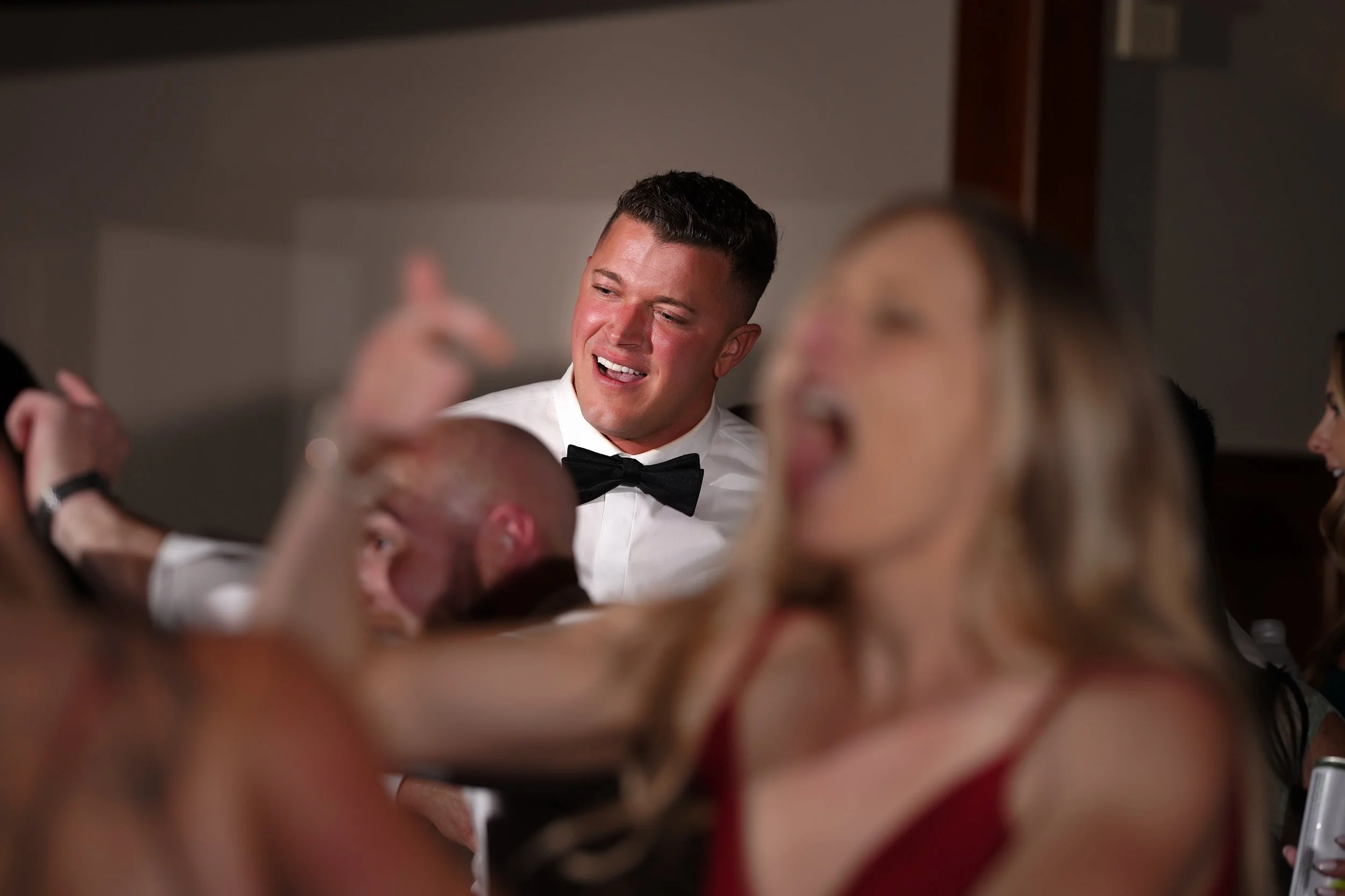 Groom Drew showing a joyful and animated reaction during a surprise performance at his wedding reception.