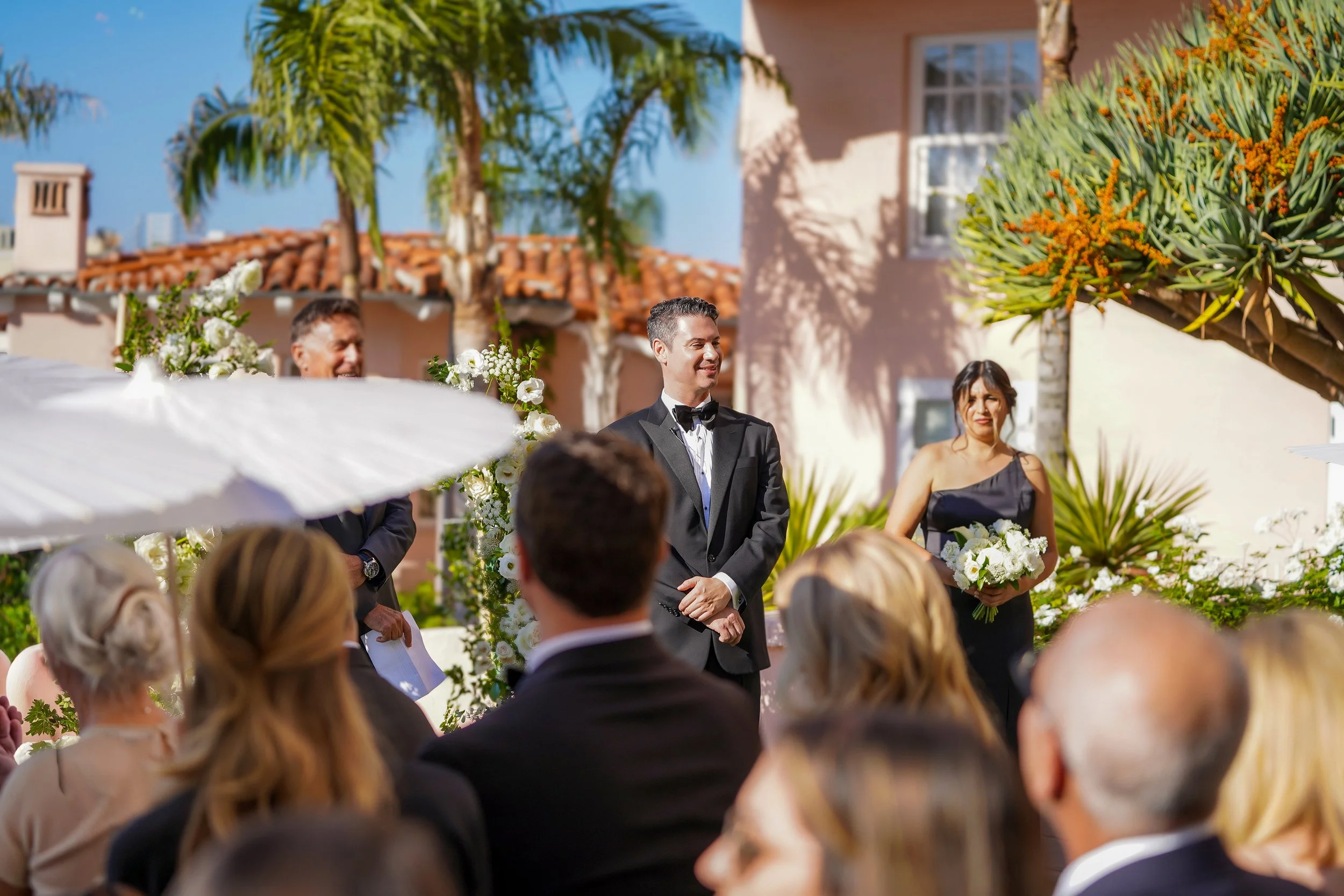 Luxury outdoor wedding ceremony in La Jolla, California, with guests seated under white umbrellas.