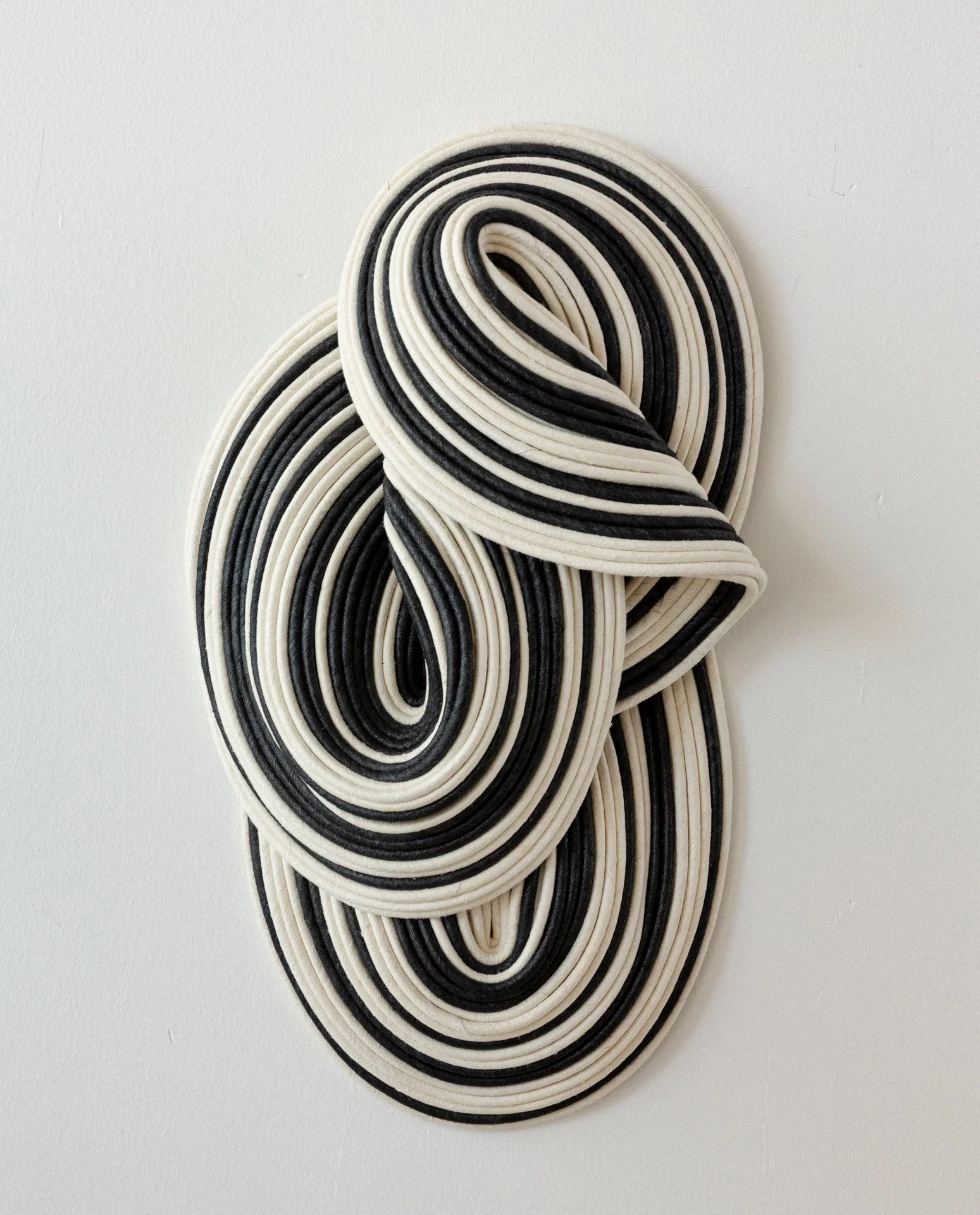 Close-up of black and white rubber bands arranged in circular patterns on a white background.