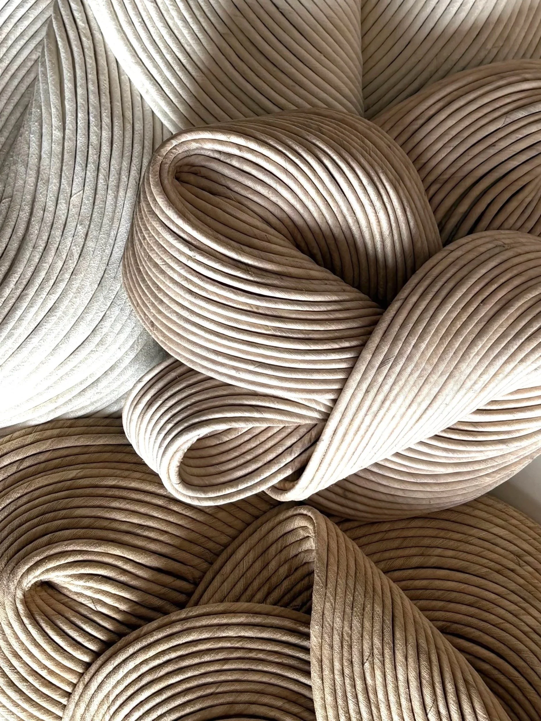Close-up of intertwined, ribbed fabric in shades of beige and champagne.