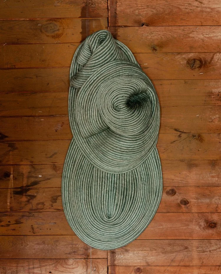 A folded green and beige striped rug on a wooden floor.