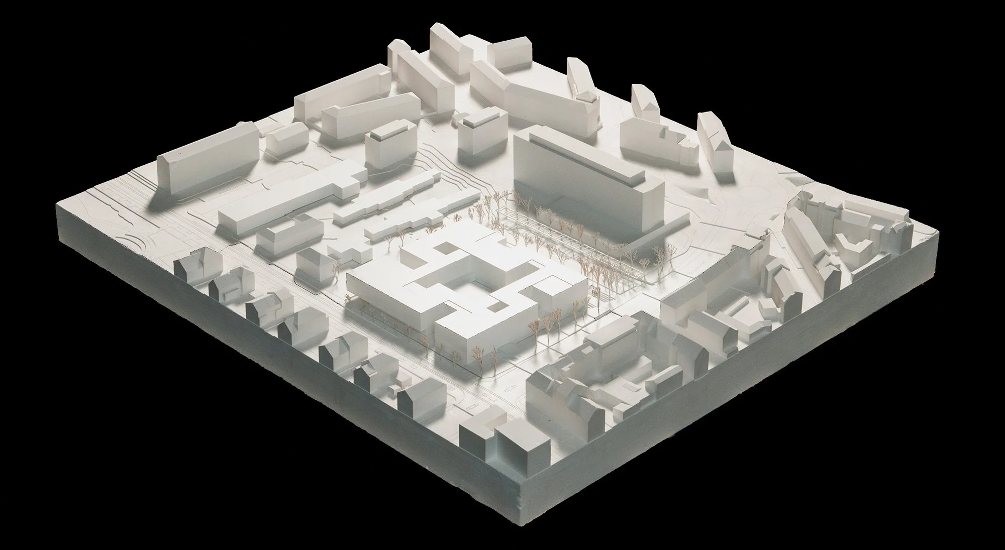 Architektonisches Modell einer städtischen Planung mit weißen Gebäuden, Straßen und Bäumen in der Mitte auf schwarzem Hintergrund