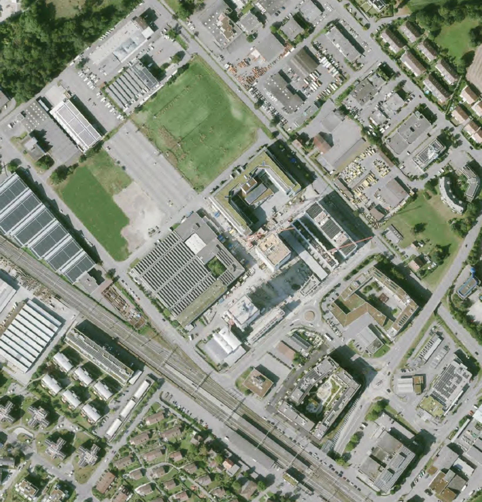 Luftaufnahme einer städtischen Gegend mit Gebäuden, Parks, Straßen und Eisenbahnlinien.