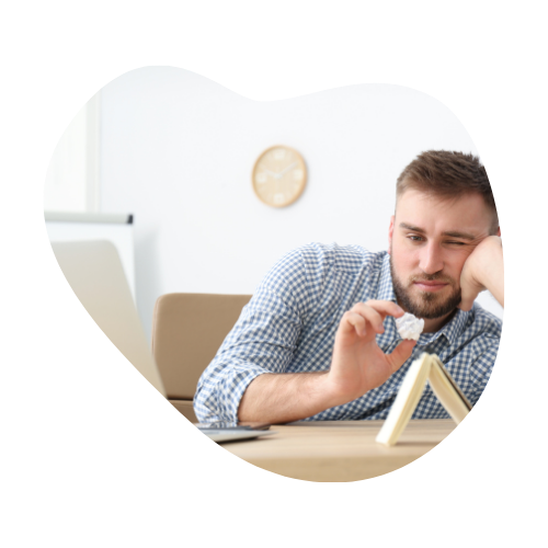 A bored man sitting at a desk, leaning on one arm and playing with a fidget toy, symbolizing the struggle with focus and low dopamine levels in ADHD.