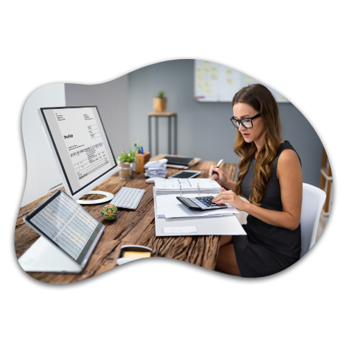 Woman in glasses working at a desk with a computer and paperwork, managing complex tasks