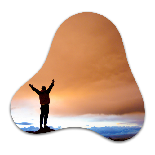 Person standing on a hilltop with arms raised at sunset, embracing empowerment
