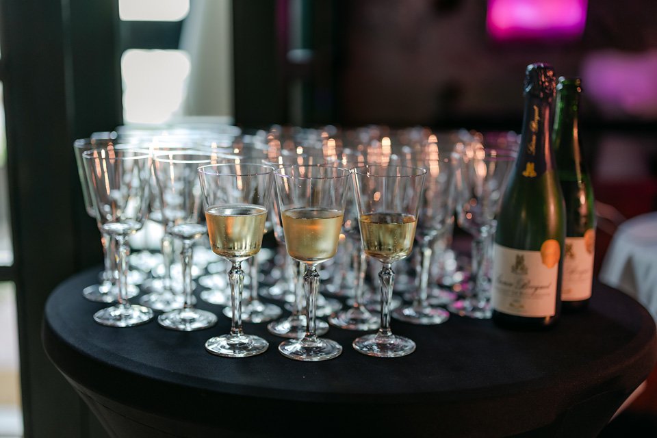 A table with multiple empty and filled champagne glasses and two bottles of champagne, set up for a celebration or event.